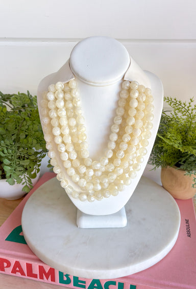 Add a soft, timeless touch to your look with this eye-catching ivory layered beaded necklace. Featuring seven strands of ivory beads, this chunky statement piece creates a full, dimensional look that makes even the simplest outfit feel a little more fun. The faux leather backing helps keep each layer beautifully arranged, while the magnetic closure makes it easy to put on and take off. It’s the perfect finishing touch for sweaters, dresses, blouses, and everyday basics.