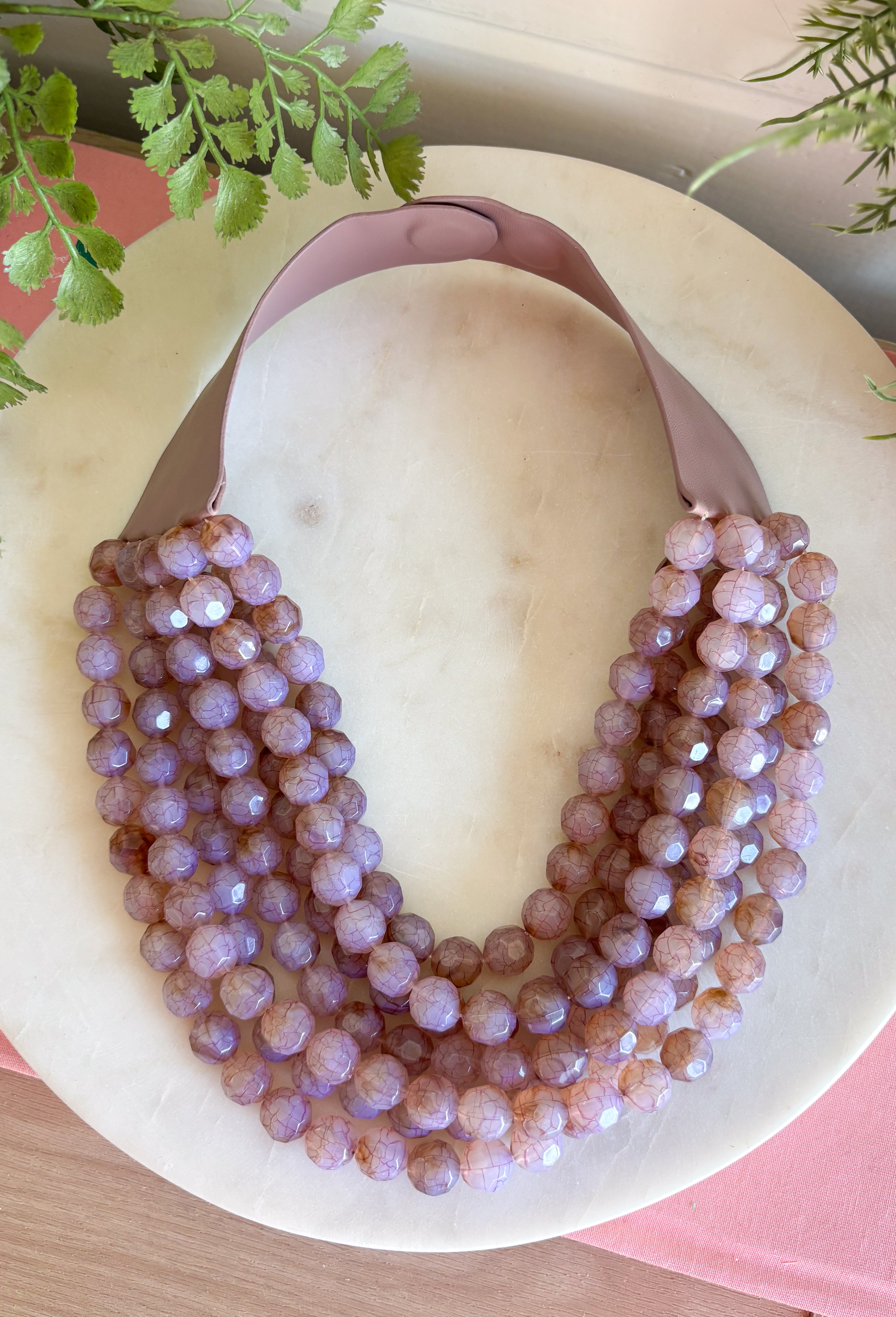 Add a pretty pop of purple to your look with this eye-catching layered beaded necklace. Featuring seven strands of light purple beads, this chunky statement piece creates a full, dimensional look that makes even the simplest outfit feel a little more fun. The faux leather backing helps keep each layer beautifully arranged, while the magnetic closure makes it easy to put on and take off. It’s the perfect finishing touch for sweaters, dresses, blouses, and everyday basics.