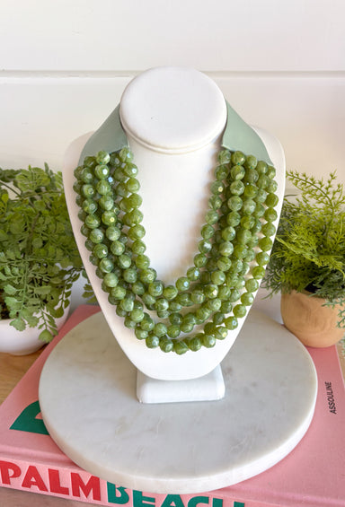 Add a pretty pop of olive to your look with this eye-catching layered beaded necklace. Featuring seven strands of light purple beads, this chunky statement piece creates a full, dimensional look that makes even the simplest outfit feel a little more fun. The faux leather backing helps keep each layer beautifully arranged, while the magnetic closure makes it easy to put on and take off. It’s the perfect finishing touch for sweaters, dresses, blouses, and everyday basics.