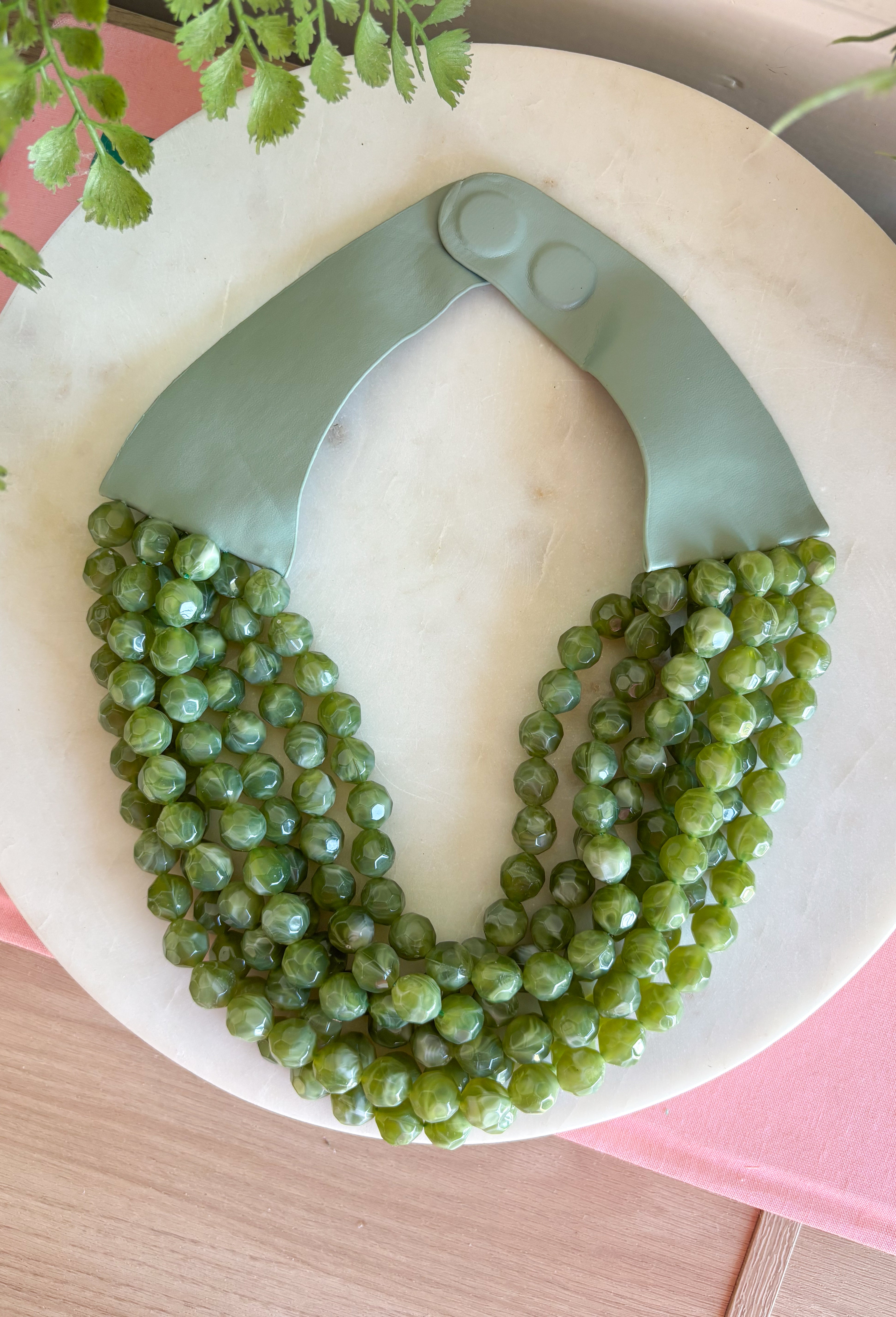 Add a pretty pop of olive to your look with this eye-catching layered beaded necklace. Featuring seven strands of light purple beads, this chunky statement piece creates a full, dimensional look that makes even the simplest outfit feel a little more fun. The faux leather backing helps keep each layer beautifully arranged, while the magnetic closure makes it easy to put on and take off. It’s the perfect finishing touch for sweaters, dresses, blouses, and everyday basics.