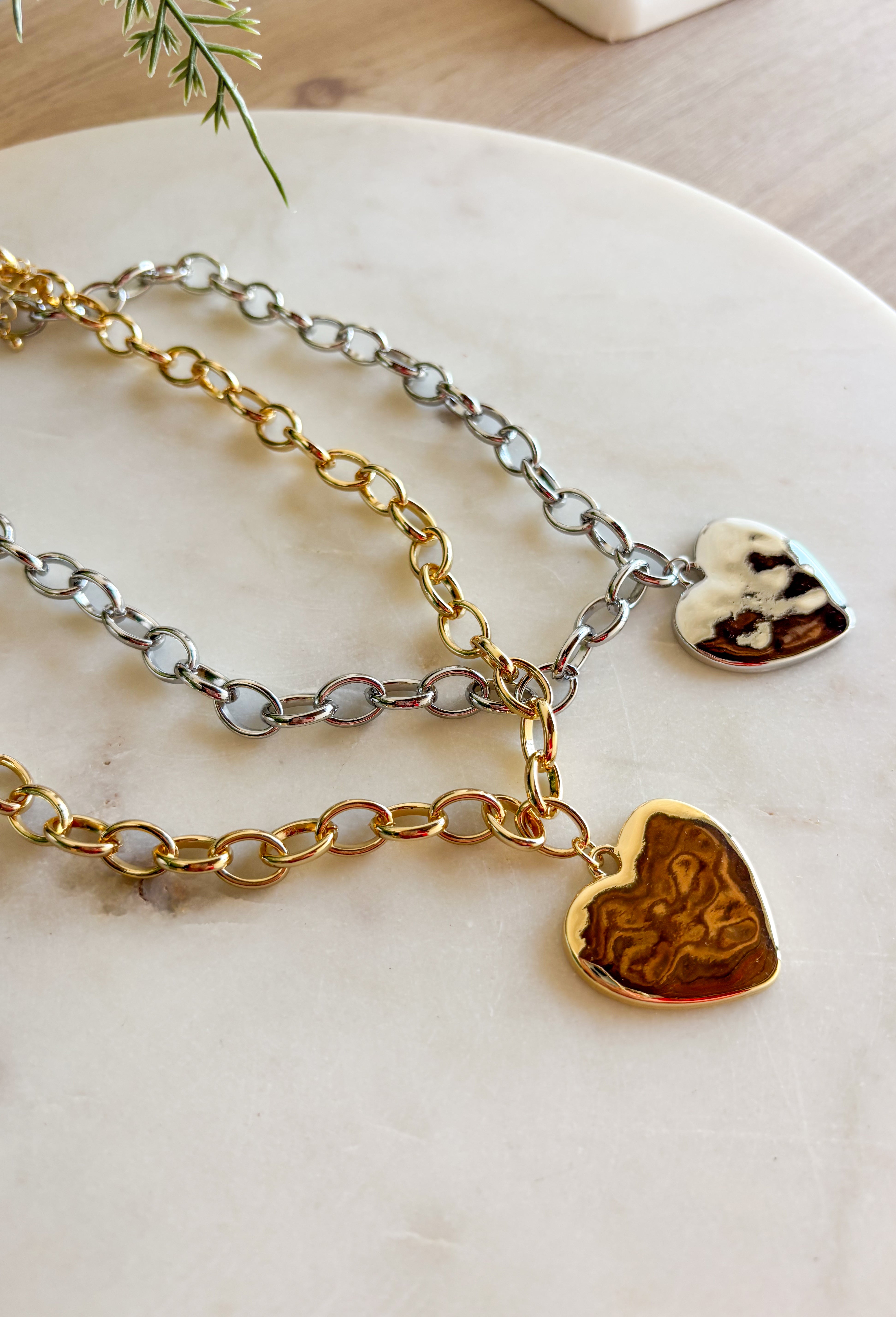 Simple, stylish, and oh-so versatile—this gold chain necklace is the perfect finishing touch for any look. Designed with a textured heart charm, it adds just the right amount of detail and personality without overpowering your outfit. With its adjustable extender, you can wear it closer to the neckline for layering or a little longer on its own. A timeless piece you’ll keep reaching for, no matter the occasion.