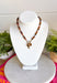 Rich earthy tones and meaningful details come together beautifully in this charm necklace that's perfect for the fall season. Featuring warm brown beads, this eye-catching piece is adorned with a mix of charms, including a gold cross, a natural brown stone, a sparkling brown crystal, and hammered gold accents for added texture and shine. Whether worn with a cozy sweater or your favorite dress, this unique necklace adds effortless charm and personality to every outfit.