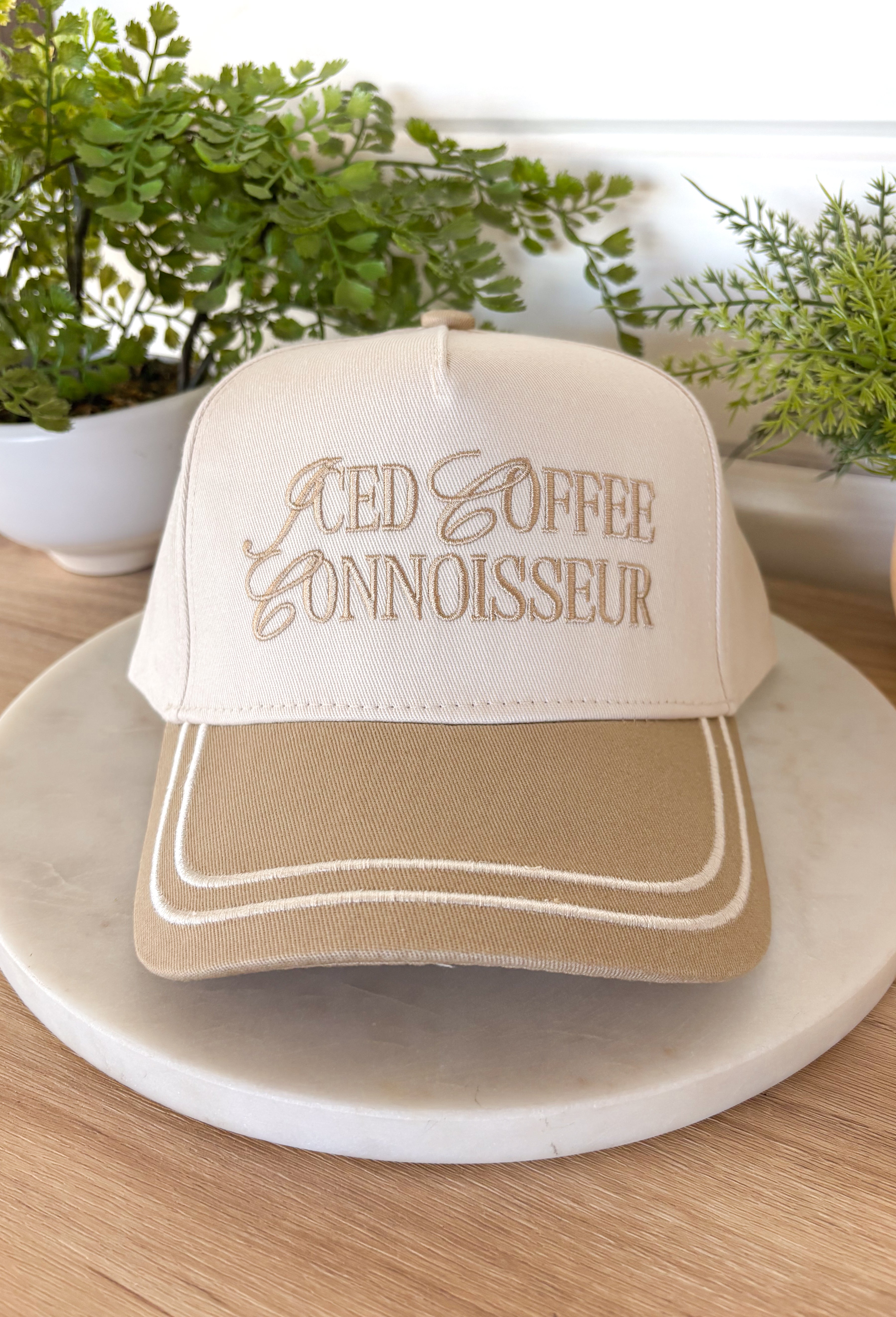 This neutral trucker hat with tan accents is a must-have for all the iced coffee lovers out there. Featuring “Iced Coffee Connoisseur” embroidered across the front, it adds a fun, laid-back touch to your everyday outfits. The neutral color palette keeps it easy to style, while the adjustable back offers a comfortable, custom fit for all-day wear. Perfect for coffee runs, casual days, and sunny spring outings, this hat is equal parts playful and practical.