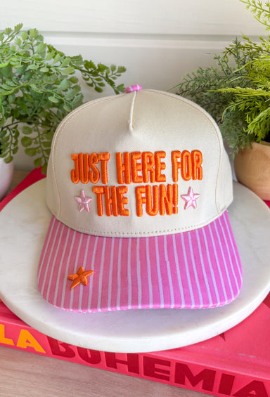 Bring a little extra fun wherever you go with this playful trucker hat! Featuring "Just Here For The Fun" embroidered in bright orange, this hat is made for football Saturdays, fall festivals, road trips, and spontaneous adventures. The pink bill with neutral stripes adds the perfect pop of color, while the light pink and orange embroidered stars give it a cheerful finishing touch. 
