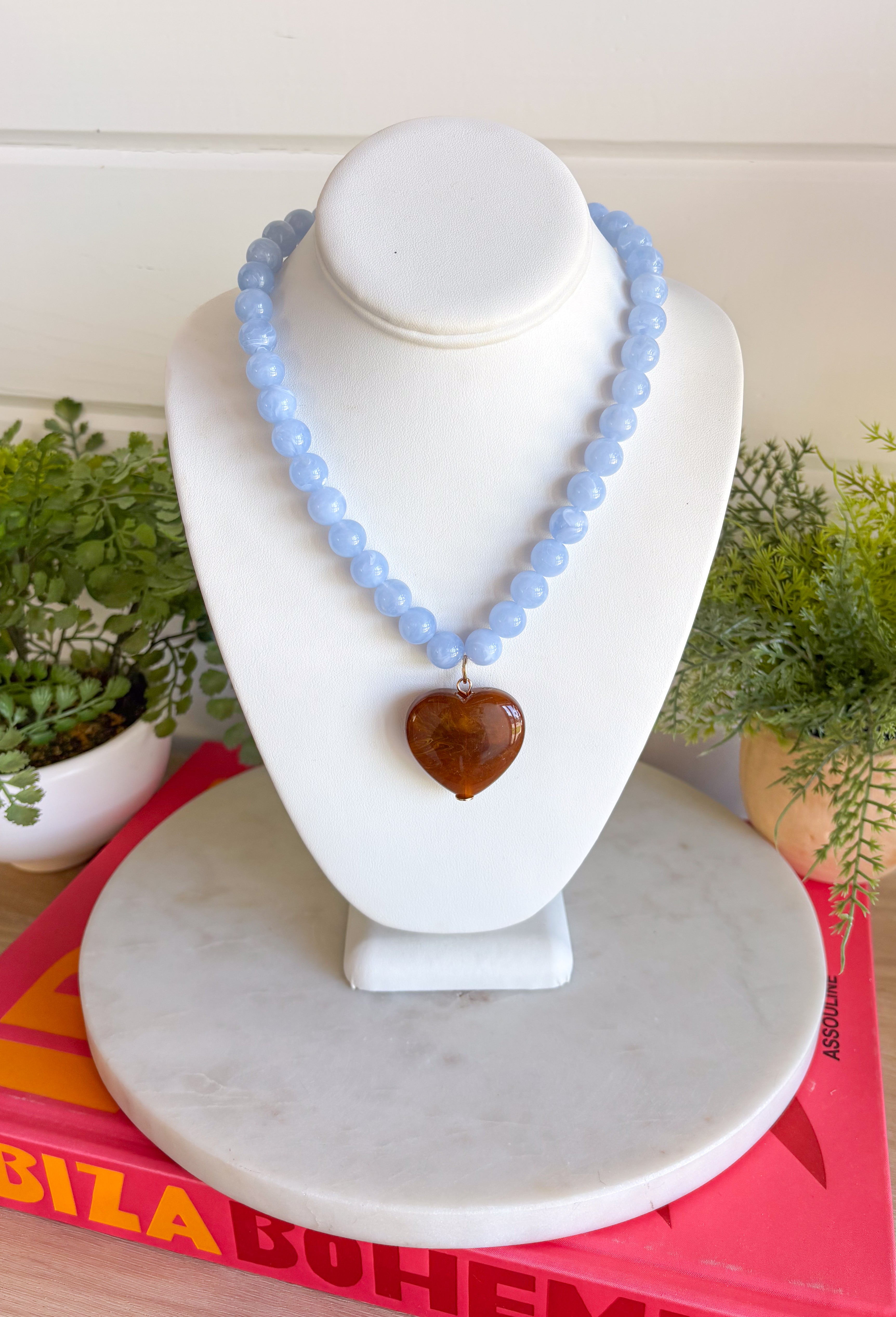Fun, playful, and full of personality! This necklace features light blue beading paired with a brown heart pendant for the perfect touch of contrast. Lightweight and easy to style, this necklace looks just as cute worn on its own as it does layered with your favorite chains and beaded pieces. It’s the perfect finishing touch for adding a subtle pop of color to your everyday outfits.