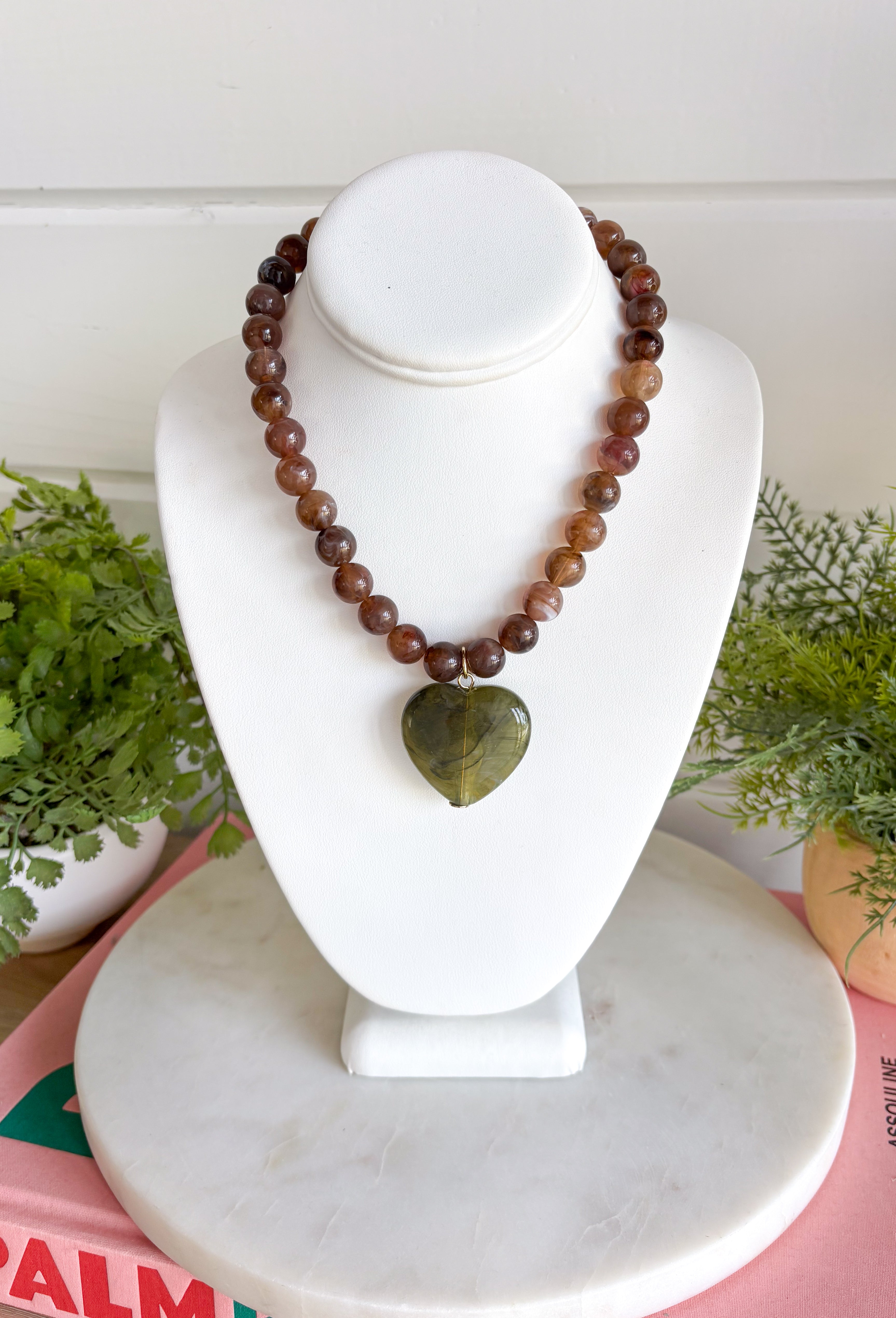 Fun, playful, and full of personality. This necklace features brown beading paired with a olive heart pendant for the perfect touch of contrast. Lightweight and easy to style, this necklace looks just as cute worn on its own as it does layered with your favorite chains and beaded pieces. It’s the perfect finishing touch for adding a subtle pop of color to your everyday outfits.