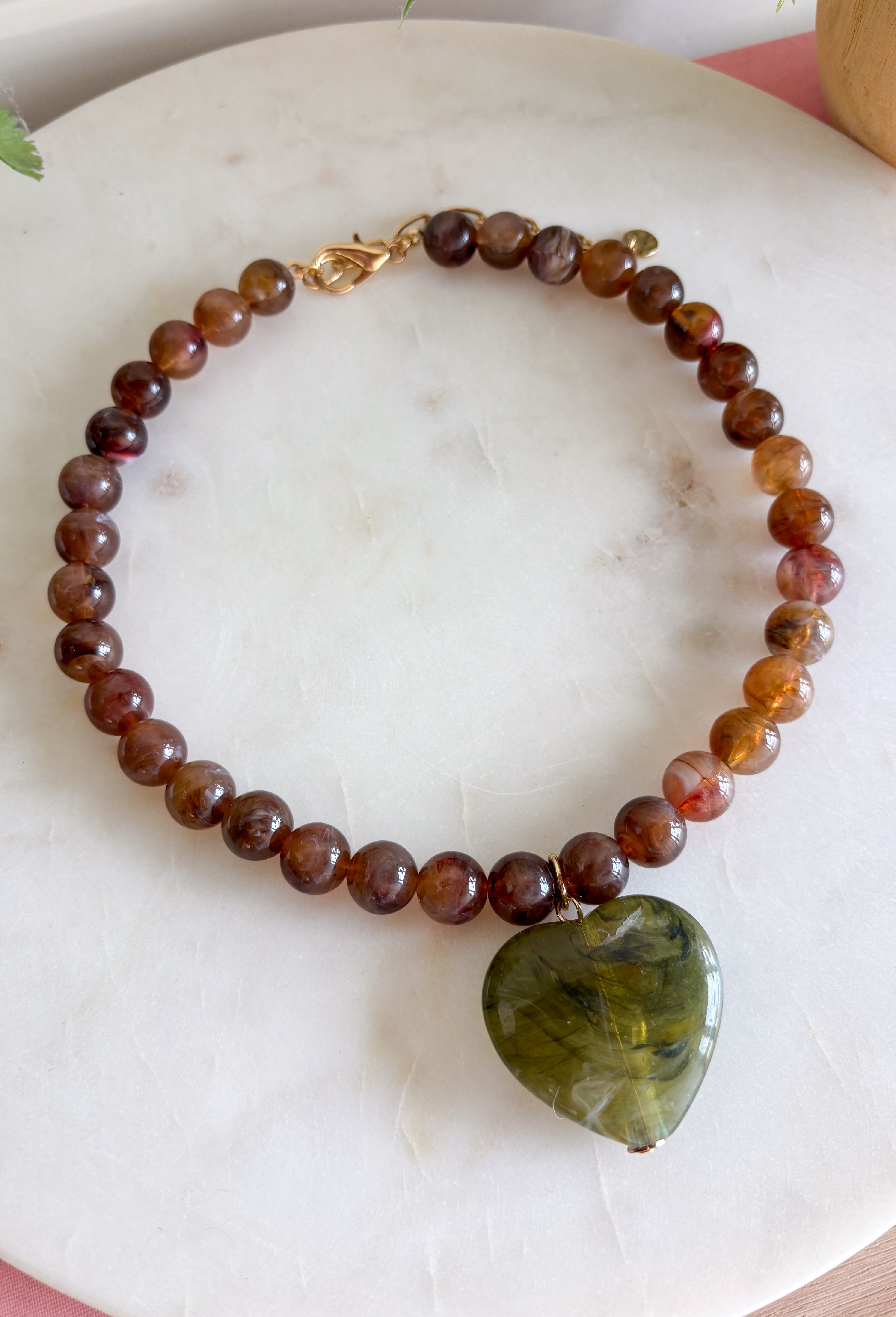 Fun, playful, and full of personality. This necklace features brown beading paired with a olive heart pendant for the perfect touch of contrast. Lightweight and easy to style, this necklace looks just as cute worn on its own as it does layered with your favorite chains and beaded pieces. It’s the perfect finishing touch for adding a subtle pop of color to your everyday outfits.