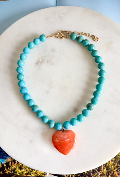 Bright, playful, and full of personality! This turquoise beaded necklace features a vibrant orange heart pendant that adds the perfect pop of color. The combination of the cool turquoise beads and the bold heart charm creates a fun, eye-catching look that instantly brightens any outfit. Lightweight and easy to style, this necklace looks just as cute worn on its own as it does layered with your favorite chains and beaded pieces. 