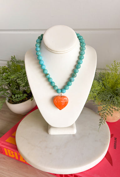 Bright, playful, and full of personality! This turquoise beaded necklace features a vibrant orange heart pendant that adds the perfect pop of color. The combination of the cool turquoise beads and the bold heart charm creates a fun, eye-catching look that instantly brightens any outfit. Lightweight and easy to style, this necklace looks just as cute worn on its own as it does layered with your favorite chains and beaded pieces. 