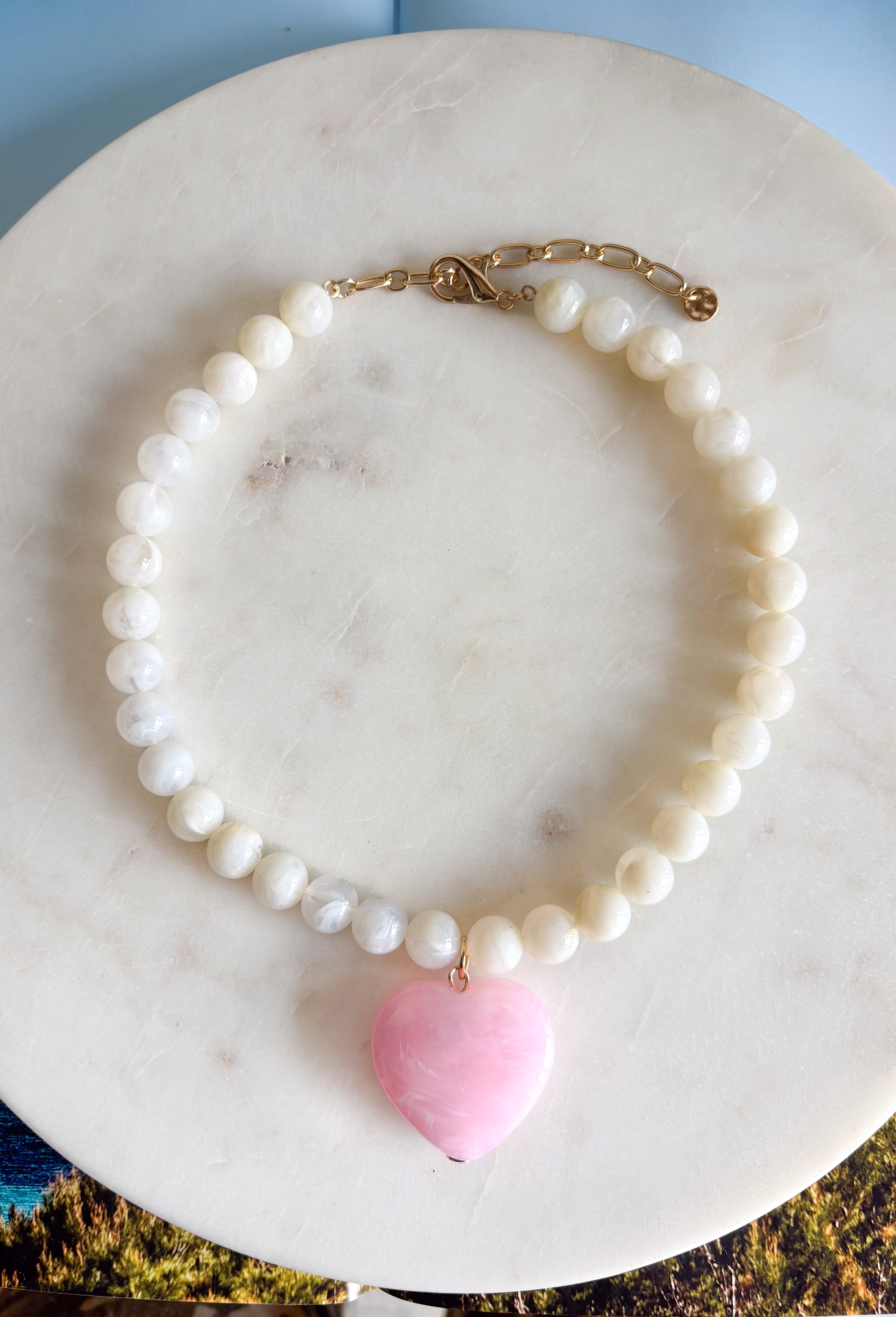Sweet, playful, and full of charm! This white beaded necklace features a light pink heart pendant that adds the perfect soft pop of color. The combination of crisp white beads and the blush heart charm creates a fresh, feminine look that’s easy to style for everyday wear. Lightweight and easy to layer, this necklace looks just as cute worn on its own as it does stacked with your favorite gold or beaded pieces. It’s a simple way to add a little love and personality to any outfit.