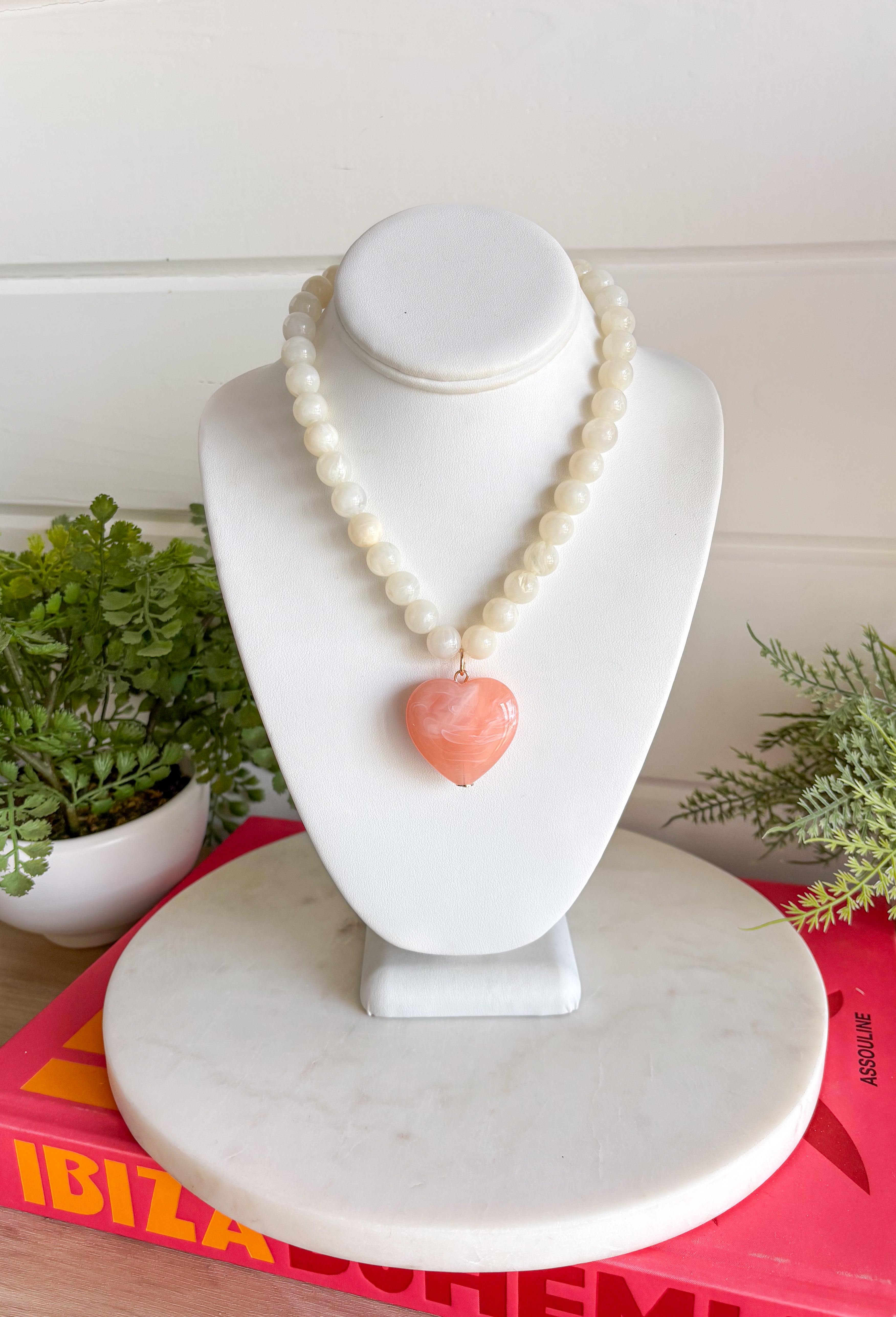 Sweet, playful, and full of charm! This white beaded necklace features a light pink heart pendant that adds the perfect soft pop of color. The combination of crisp white beads and the blush heart charm creates a fresh, feminine look that’s easy to style for everyday wear. Lightweight and easy to layer, this necklace looks just as cute worn on its own as it does stacked with your favorite gold or beaded pieces. It’s a simple way to add a little love and personality to any outfit.