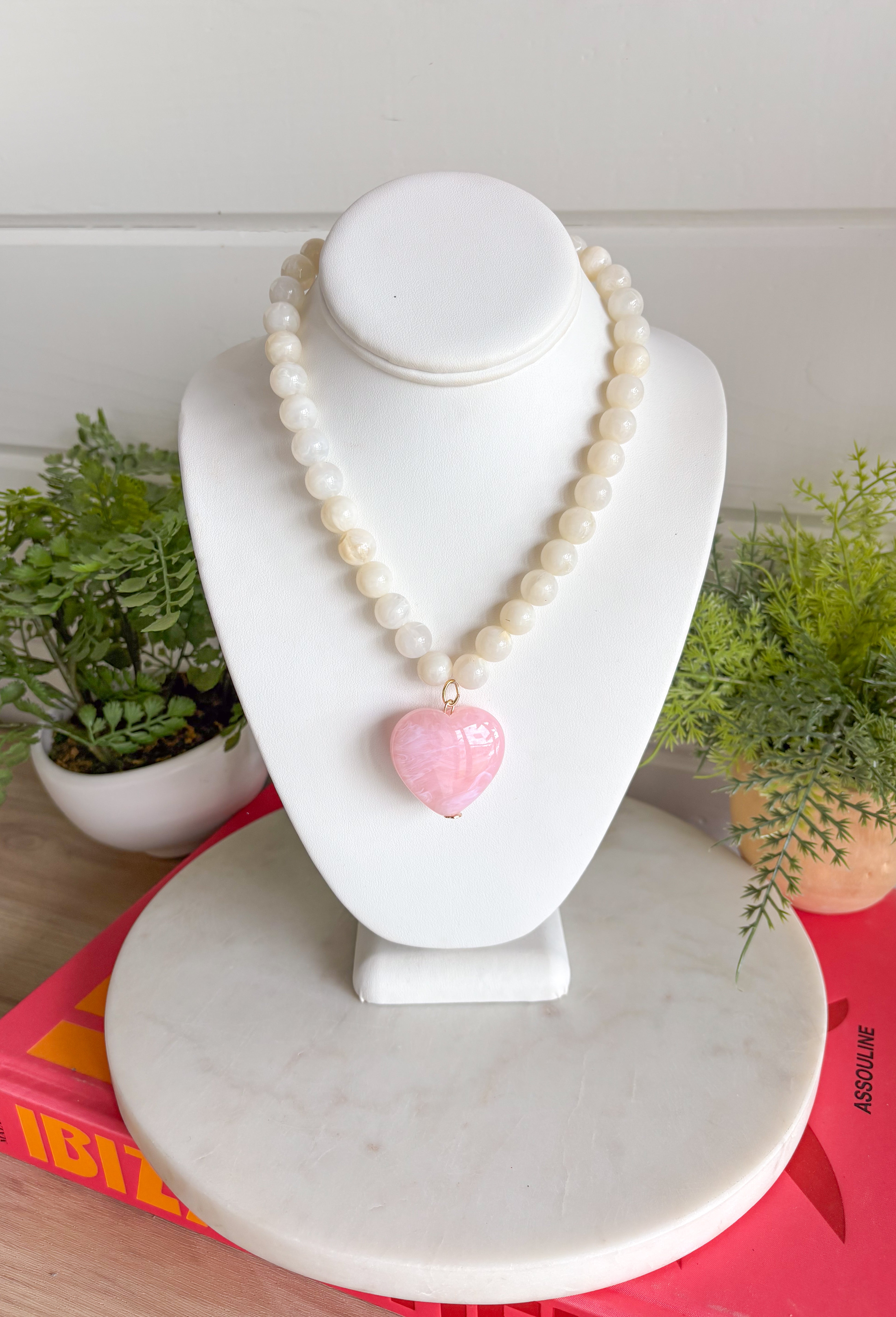 Sweet, playful, and full of charm! This white beaded necklace features a light pink heart pendant that adds the perfect soft pop of color. The combination of crisp white beads and the blush heart charm creates a fresh, feminine look that’s easy to style for everyday wear. Lightweight and easy to layer, this necklace looks just as cute worn on its own as it does stacked with your favorite gold or beaded pieces. It’s a simple way to add a little love and personality to any outfit.