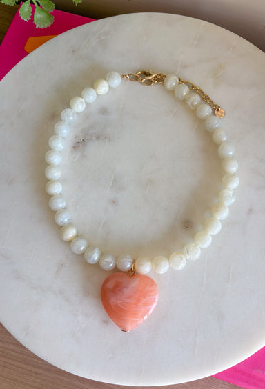Sweet, playful, and full of charm! This white beaded necklace features a light pink heart pendant that adds the perfect soft pop of color. The combination of crisp white beads and the blush heart charm creates a fresh, feminine look that’s easy to style for everyday wear. Lightweight and easy to layer, this necklace looks just as cute worn on its own as it does stacked with your favorite gold or beaded pieces. It’s a simple way to add a little love and personality to any outfit.