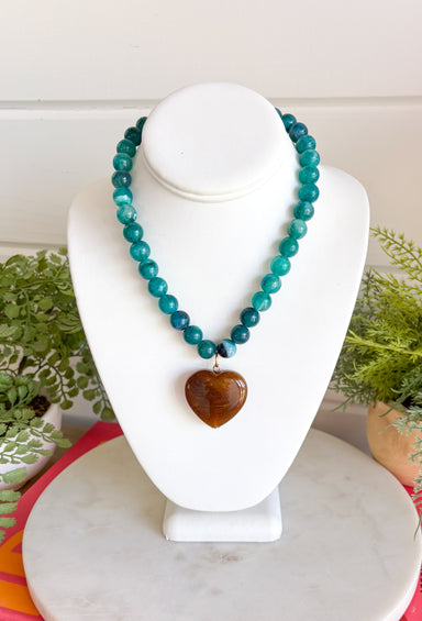 Fun, playful, and full of personality!&nbsp;This necklace features teal beading paired with a brown heart pendant for the perfect touch of contrast. Lightweight and easy to style, this necklace looks just as cute worn on its own as it does layered with your favorite chains and beaded pieces. It’s the perfect finishing touch for adding a subtle pop of color to your everyday outfits.