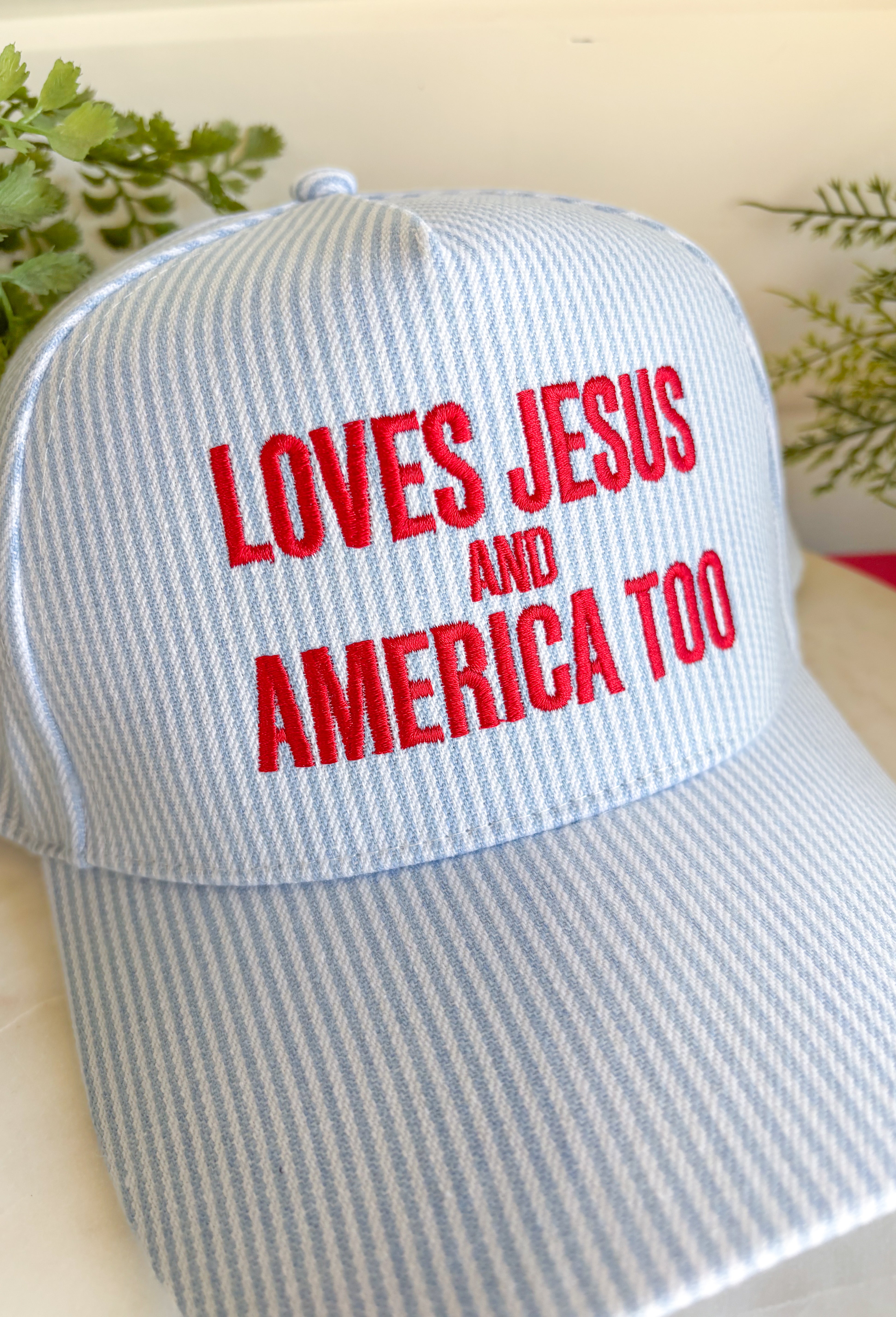 This light blue and white stripe trucker hat is made for celebrating faith, freedom, and all the 4th of July fun! Featuring “Loves Jesus And America Too” embroidered in red, it brings the perfect mix of patriotic spirit and meaningful style. The striped design keeps it fresh and festive, while the adjustable fit makes it easy to wear all day—from parades and lake days to backyard BBQs and fireworks. It’s the kind of hat that adds personality to any casual outfit and feels right at home all summer long. 