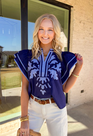 Classic with a fun spring twist, this short sleeve navy top by Entro is an easy everyday favorite. Featuring a bold blue and white stripe motif on the front, it adds the perfect pop of pattern while still feeling clean and timeless. Matching blue and white stripe trim throughout gives it an extra polished touch, making it a simple top that still feels special. Lightweight and comfy, it pairs effortlessly with denim, shorts, or a crisp white skirt for spring.
