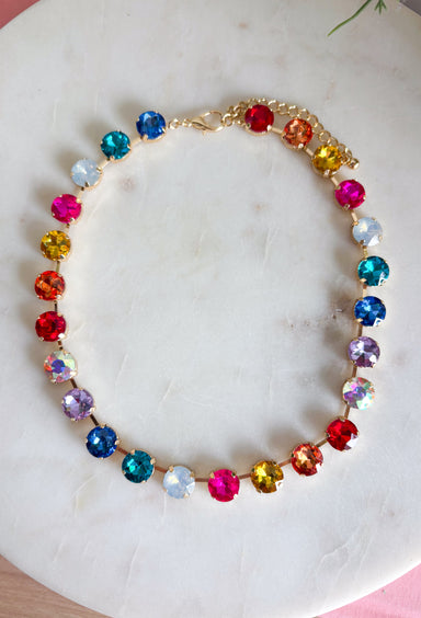 Add a meaningful touch of color to your jewelry collection with this beautiful cross necklace. Featuring a strand of colorful rhinestone crystals in shades of red, blue, green, pink, and gold, this eye-catching piece is finished with a matching cross pendant for the perfect blend of faith and style. The vibrant colors and delicate gold accents make it a standout accessory that's easy to wear for both everyday outfits and special occasions.