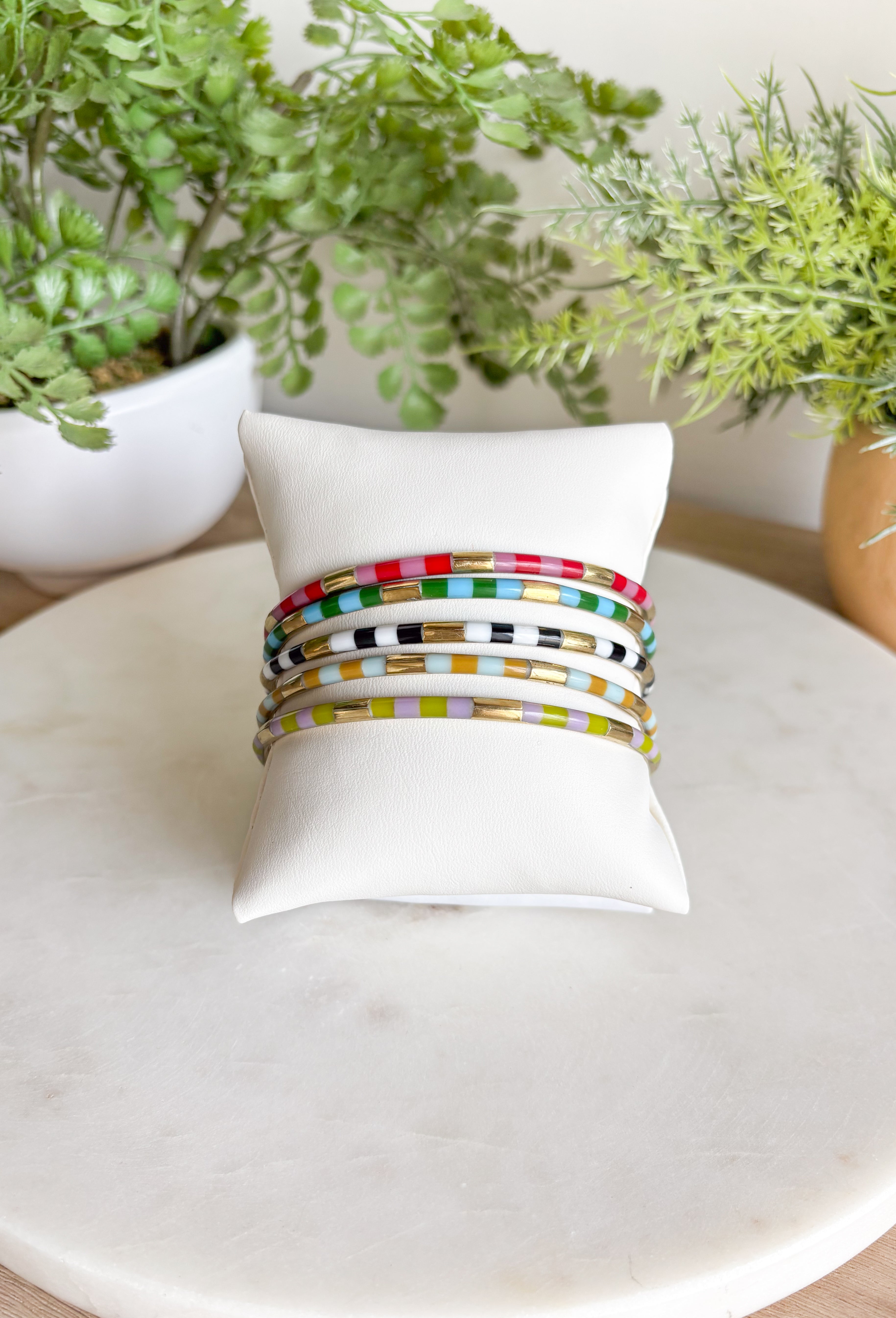 Give ‘em the RAZZLE DAZZLE with the iconic 5 bangle stack that started it all! This playful stack is brass with resin inlay and has beautiful neutrals paired with bright pops of red, pink, turquoise &amp; green while anchored by classic black and white. Stack them high with style.&nbsp;