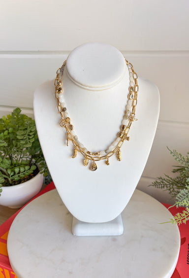 This layered necklace gives you that perfectly styled, on-trend look without any effort! Featuring a neutral beaded strand with gold accents paired with a charm-filled gold chain, it brings the perfect mix of western-inspired and playful details. With charms like a cross, heart, palm leaf, bow, and even a shoe, it adds so much personality to your outfit. Lightweight and easy to wear, it’s the ultimate throw-on accessory for summer days when you want to look put together in seconds. 