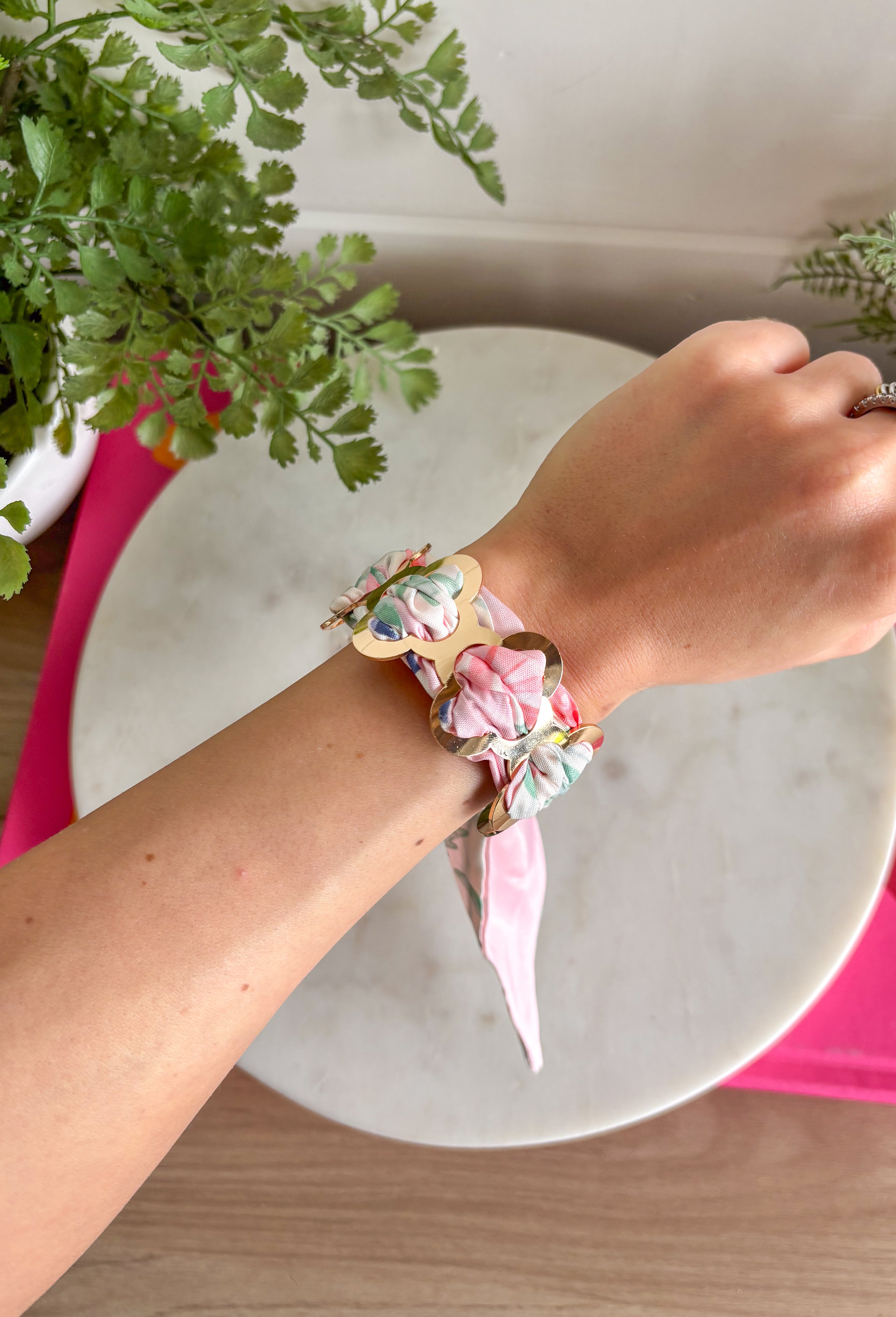 A bold statement with a feminine twist! This fabric wrapped chain link bracelet features oversized gold chain links wrapped in silky scarf-style fabric for a playful pop of color. The soft blend of pink, off white, and green creates a fresh, cheerful look that instantly brightens any outfit. The mix of polished gold and colorful fabric gives this piece a trendy yet effortless feel, making it the perfect accessory for dressing up a simple outfit or adding personality to your everyday style.