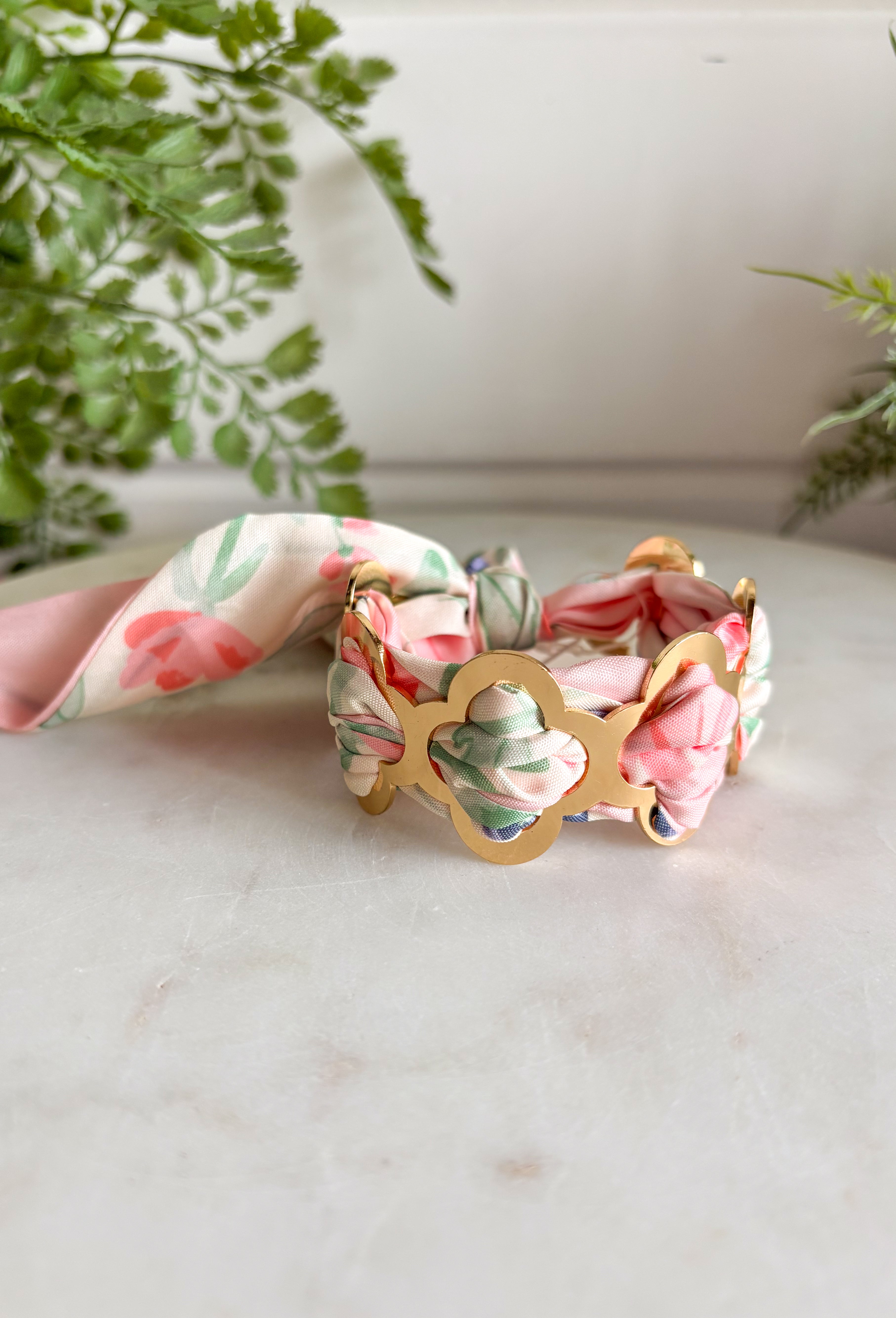 A bold statement with a feminine twist! This fabric wrapped chain link bracelet features oversized gold chain links wrapped in silky scarf-style fabric for a playful pop of color. The soft blend of pink, off white, and green creates a fresh, cheerful look that instantly brightens any outfit. The mix of polished gold and colorful fabric gives this piece a trendy yet effortless feel, making it the perfect accessory for dressing up a simple outfit or adding personality to your everyday style.