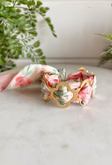 A bold statement with a feminine twist! This fabric wrapped chain link bracelet features oversized gold chain links wrapped in silky scarf-style fabric for a playful pop of color. The soft blend of pink, off white, and green creates a fresh, cheerful look that instantly brightens any outfit. The mix of polished gold and colorful fabric gives this piece a trendy yet effortless feel, making it the perfect accessory for dressing up a simple outfit or adding personality to your everyday style.