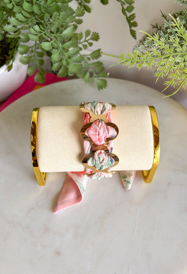 A bold statement with a feminine twist! This fabric wrapped chain link bracelet features oversized gold chain links wrapped in silky scarf-style fabric for a playful pop of color. The soft blend of pink, off white, and green creates a fresh, cheerful look that instantly brightens any outfit. The mix of polished gold and colorful fabric gives this piece a trendy yet effortless feel, making it the perfect accessory for dressing up a simple outfit or adding personality to your everyday style.