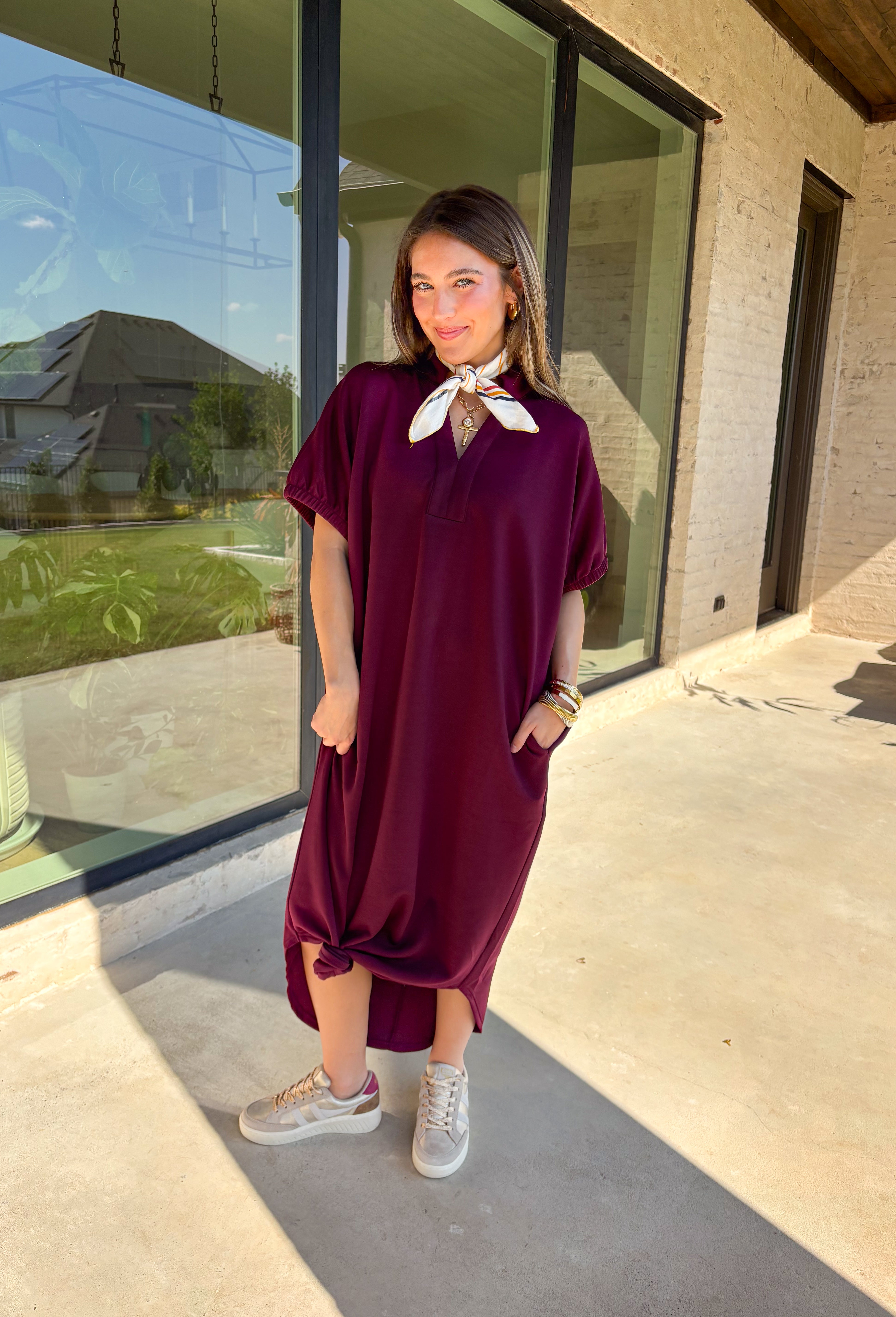 Effortless and versatile, this burgundy midi dress is an easy favorite for fall. Designed with a band collar v-neckline and elasticated short sleeves, it offers both structure and comfort. Side pockets keep it practical, while the soft, stretchy fabric blend makes it perfect for all-day wear. You'll find yourself reaching for this dress all season long!
