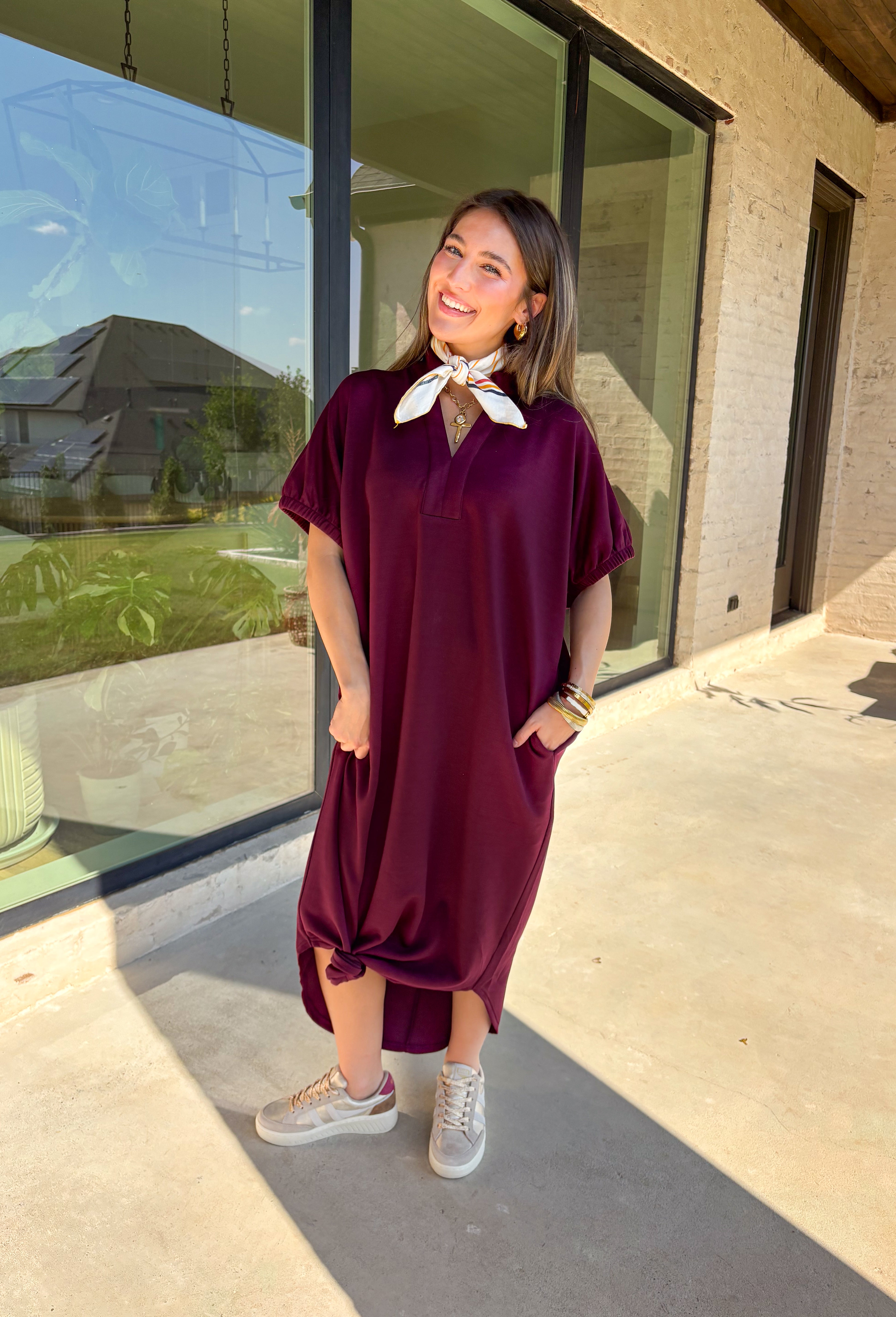 Effortless and versatile, this burgundy midi dress is an easy favorite for fall. Designed with a band collar v-neckline and elasticated short sleeves, it offers both structure and comfort. Side pockets keep it practical, while the soft, stretchy fabric blend makes it perfect for all-day wear. You'll find yourself reaching for this dress all season long!