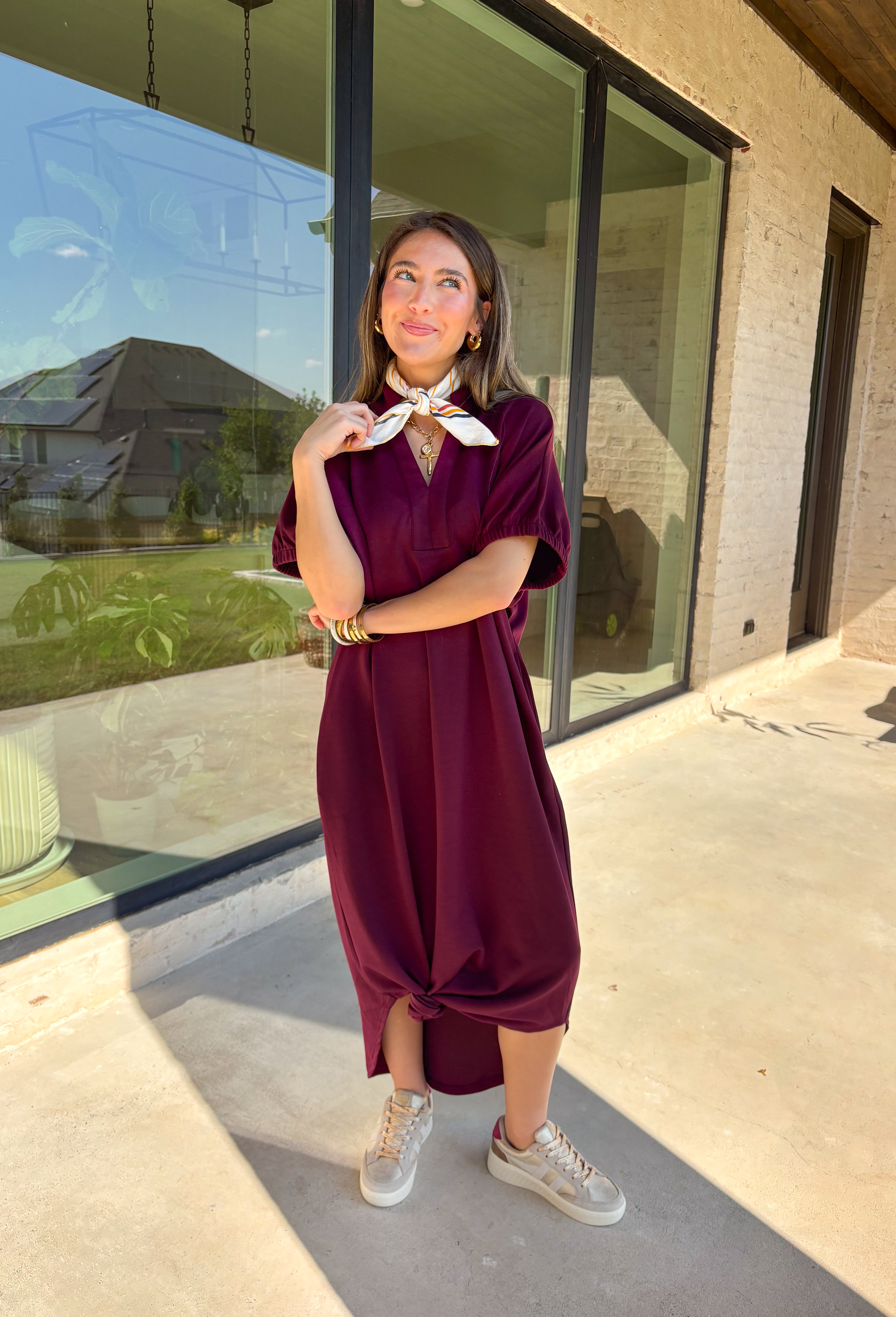 Effortless and versatile, this burgundy midi dress is an easy favorite for fall. Designed with a band collar v-neckline and elasticated short sleeves, it offers both structure and comfort. Side pockets keep it practical, while the soft, stretchy fabric blend makes it perfect for all-day wear. You'll find yourself reaching for this dress all season long!