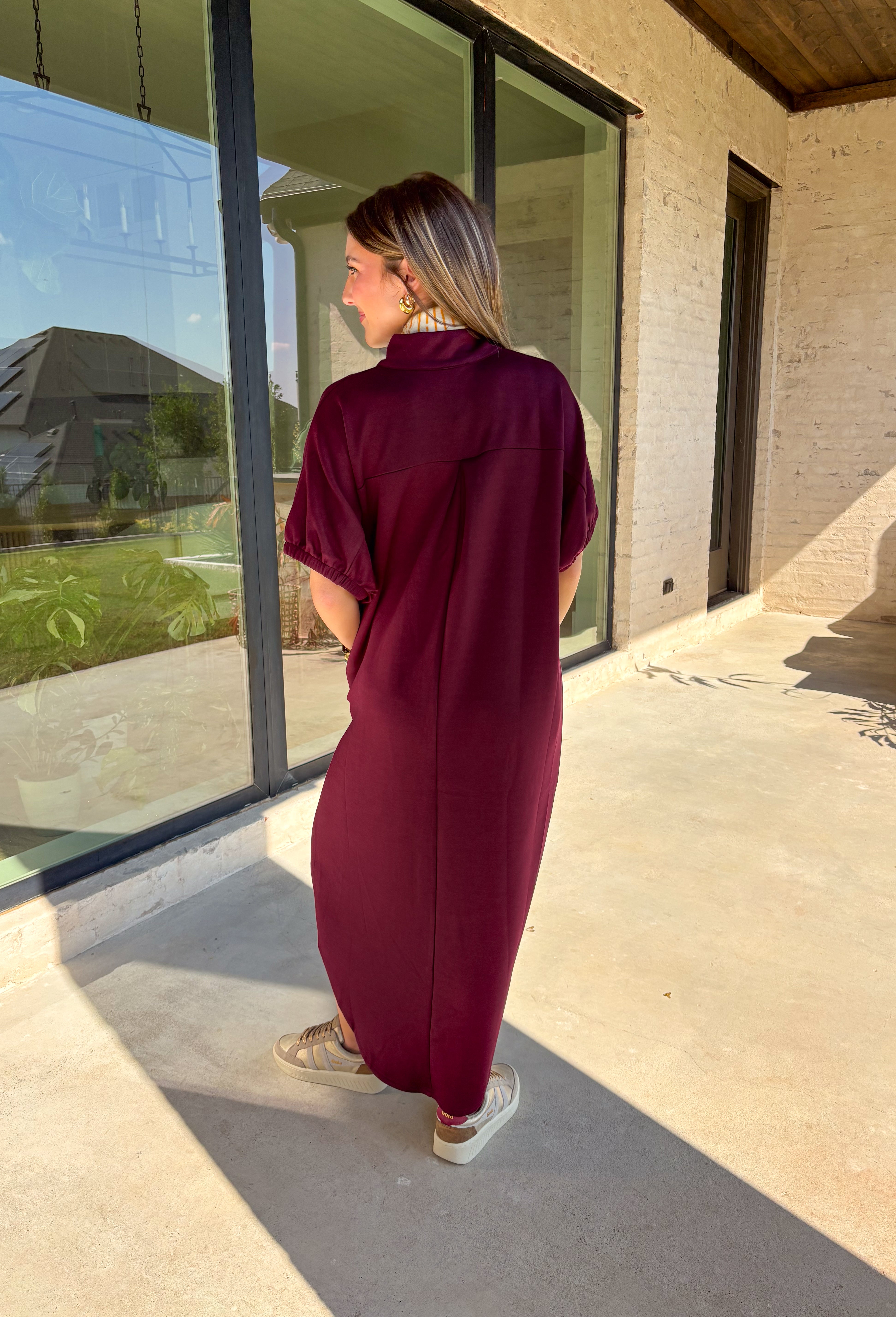 Effortless and versatile, this burgundy midi dress is an easy favorite for fall. Designed with a band collar v-neckline and elasticated short sleeves, it offers both structure and comfort. Side pockets keep it practical, while the soft, stretchy fabric blend makes it perfect for all-day wear. You'll find yourself reaching for this dress all season long!