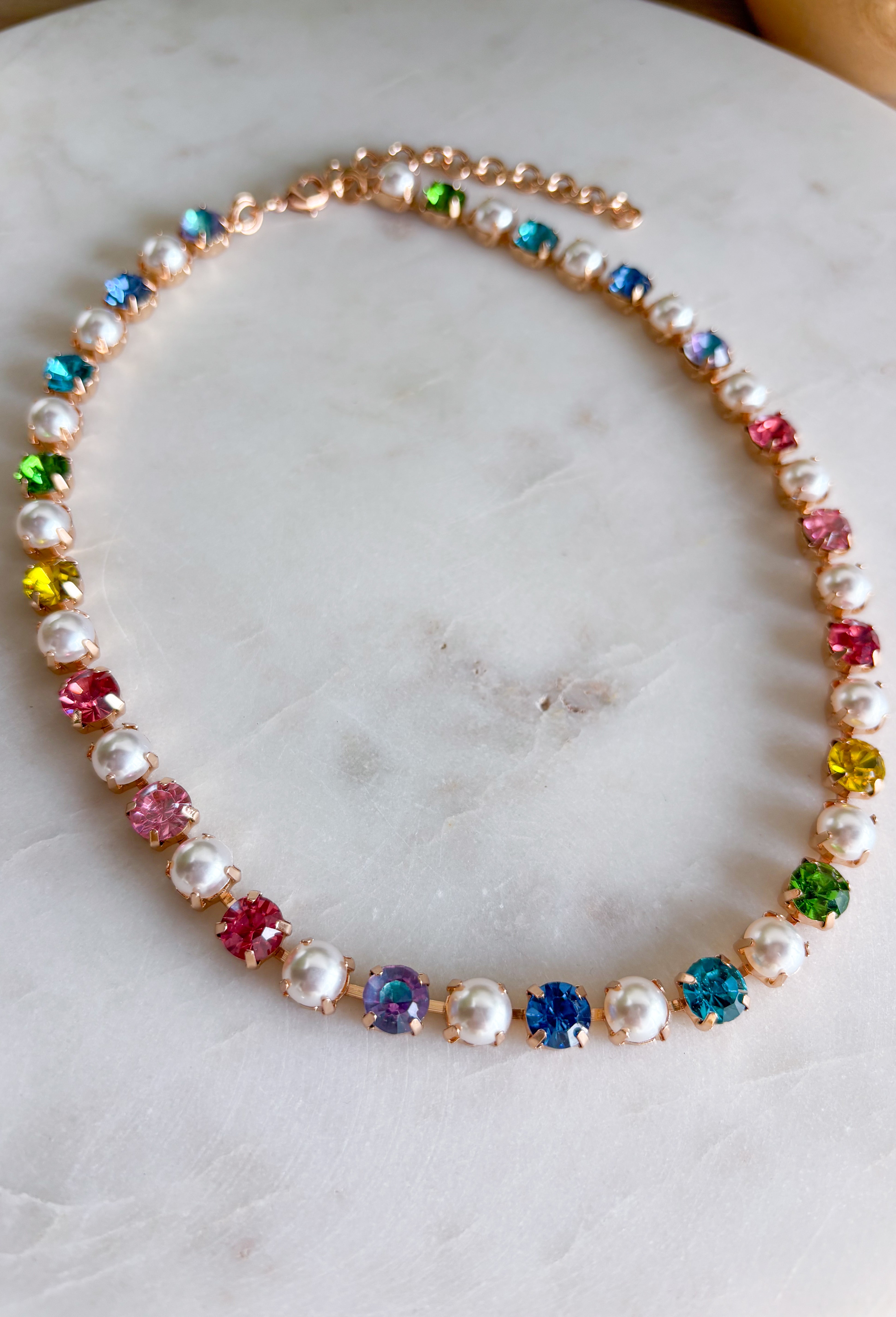 This pastel gemstone necklace brings a soft, dreamy touch to your spring accessory lineup. Featuring faceted crystal stones in gentle pastel hues, it’s beautifully accented with pearl details throughout for an added layer of elegance and charm. Each stone is set in a warm gold setting, giving the necklace a polished feel while still keeping it light and playful. It’s the perfect piece for brightening up everyday outfits or adding a romantic finishing touch to dresses and blouses.