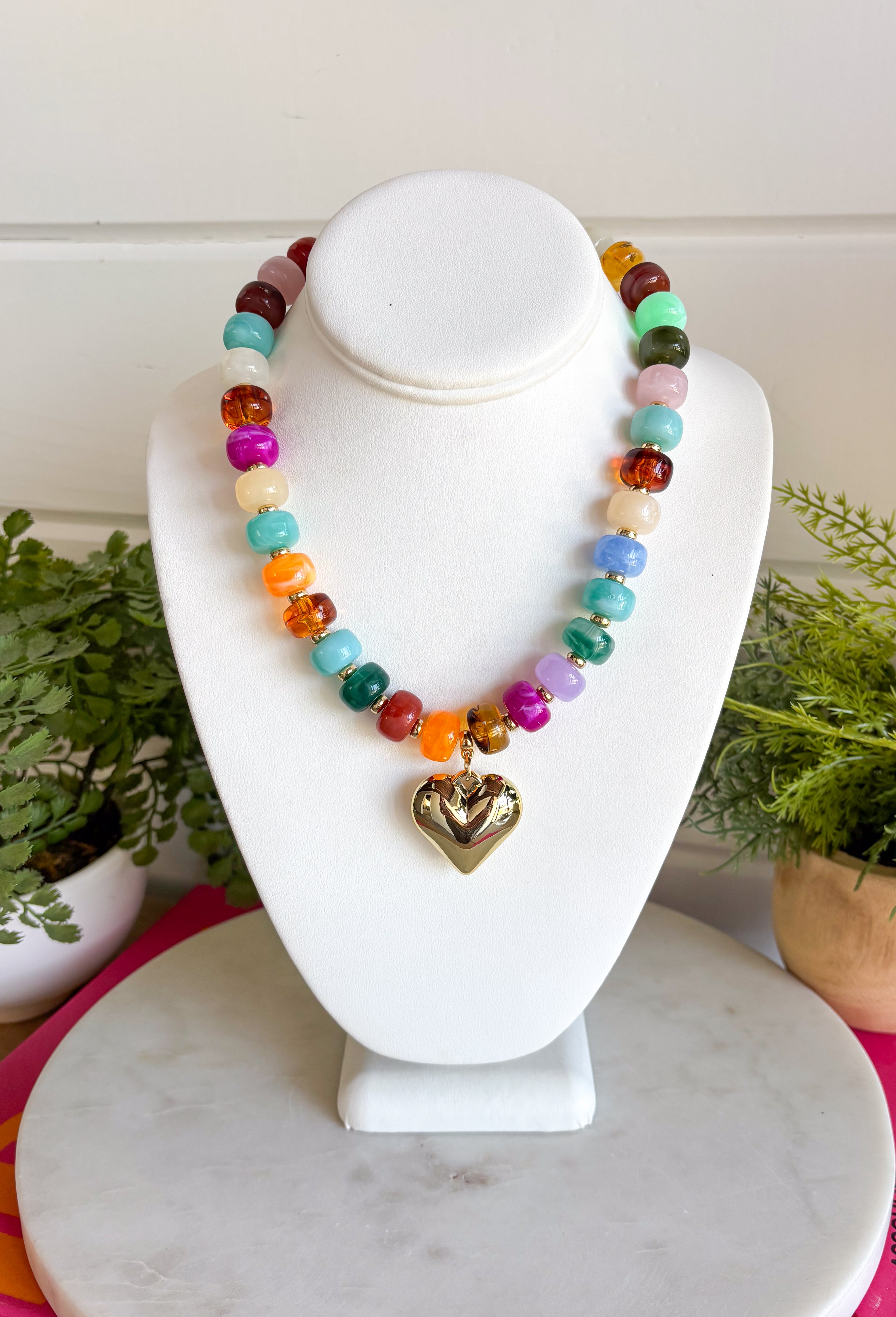 Add a meaningful finishing touch to your favorite outfits with this beautifully crafted beaded necklace. Featuring rich shades of autumn beads accented with delicate gold beads throughout, this timeless piece is finished with a gold heart charm for the perfect blend of classic style and everyday elegance. Whether worn on its own or layered with your favorite chains, this versatile necklace adds just the right amount of charm to everything from cozy sweaters to dresses and blouses all season long.