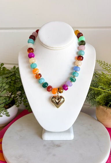 Add a meaningful finishing touch to your favorite outfits with this beautifully crafted beaded necklace. Featuring rich shades of autumn beads accented with delicate gold beads throughout, this timeless piece is finished with a gold heart charm for the perfect blend of classic style and everyday elegance. Whether worn on its own or layered with your favorite chains, this versatile necklace adds just the right amount of charm to everything from cozy sweaters to dresses and blouses all season long.