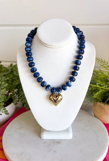 Add a meaningful finishing touch to your favorite outfits with this beautifully crafted beaded necklace. Featuring rich navy beads accented with delicate gold beads throughout, this timeless piece is finished with a gold heart charm for the perfect blend of classic style and everyday elegance. Whether worn on its own or layered with your favorite chains, this versatile necklace adds just the right amount of charm to everything from cozy sweaters to dresses and blouses all season long.