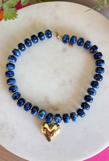 Add a meaningful finishing touch to your favorite outfits with this beautifully crafted beaded necklace. Featuring rich navy beads accented with delicate gold beads throughout, this timeless piece is finished with a gold heart charm for the perfect blend of classic style and everyday elegance. Whether worn on its own or layered with your favorite chains, this versatile necklace adds just the right amount of charm to everything from cozy sweaters to dresses and blouses all season long.