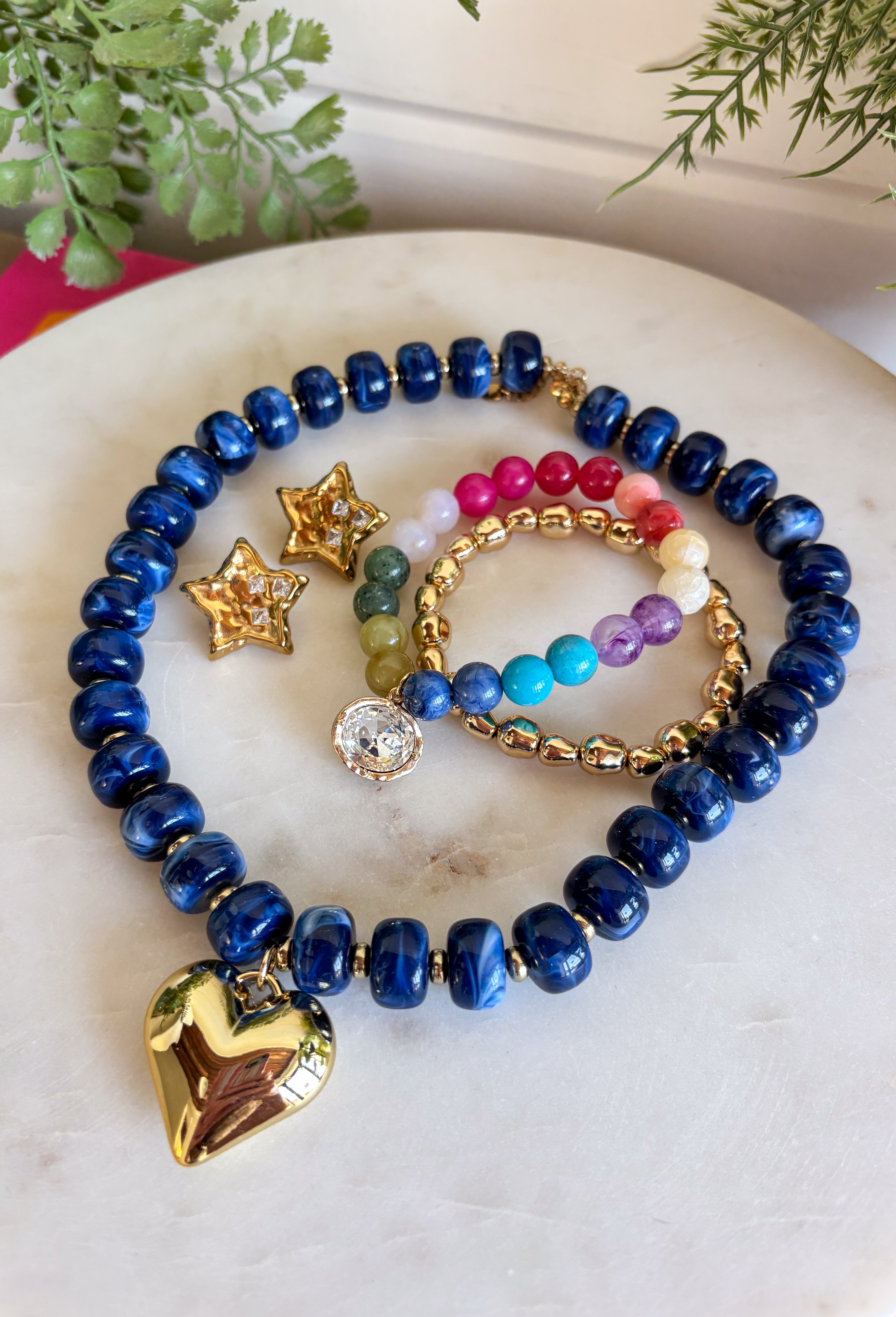 Add a meaningful finishing touch to your favorite outfits with this beautifully crafted beaded necklace. Featuring rich navy beads accented with delicate gold beads throughout, this timeless piece is finished with a gold heart charm for the perfect blend of classic style and everyday elegance. Whether worn on its own or layered with your favorite chains, this versatile necklace adds just the right amount of charm to everything from cozy sweaters to dresses and blouses all season long.