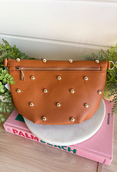 Everyone's favorite bag is back in a bold new design! The Studded Westlyn Bum Bag from Pretty Simple features the same hands-free style you love, now updated with eye-catching gold stud detailing for the perfect touch of edge. Crafted from soft vegan leather, this versatile bag can be worn as a belt bag or crossbody, making it the perfect companion for busy days, concerts, travel, shopping, and everyday adventures. Stylish, functional, and easy to wear, it's sure to become your new go-to accessory.