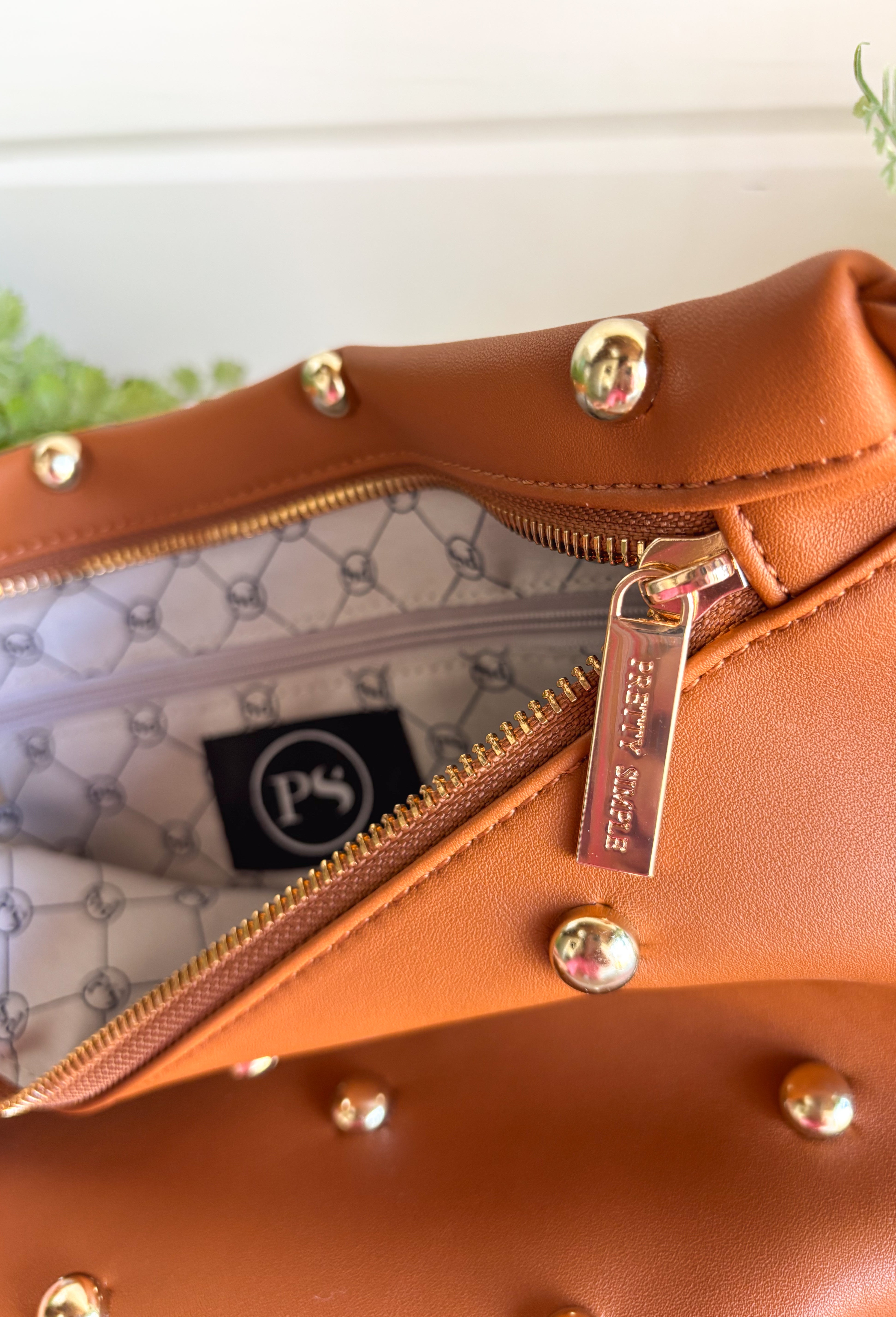Everyone's favorite bag is back in a bold new design! The Studded Westlyn Bum Bag from Pretty Simple features the same hands-free style you love, now updated with eye-catching gold stud detailing for the perfect touch of edge. Crafted from soft vegan leather, this versatile bag can be worn as a belt bag or crossbody, making it the perfect companion for busy days, concerts, travel, shopping, and everyday adventures. Stylish, functional, and easy to wear, it's sure to become your new go-to accessory.