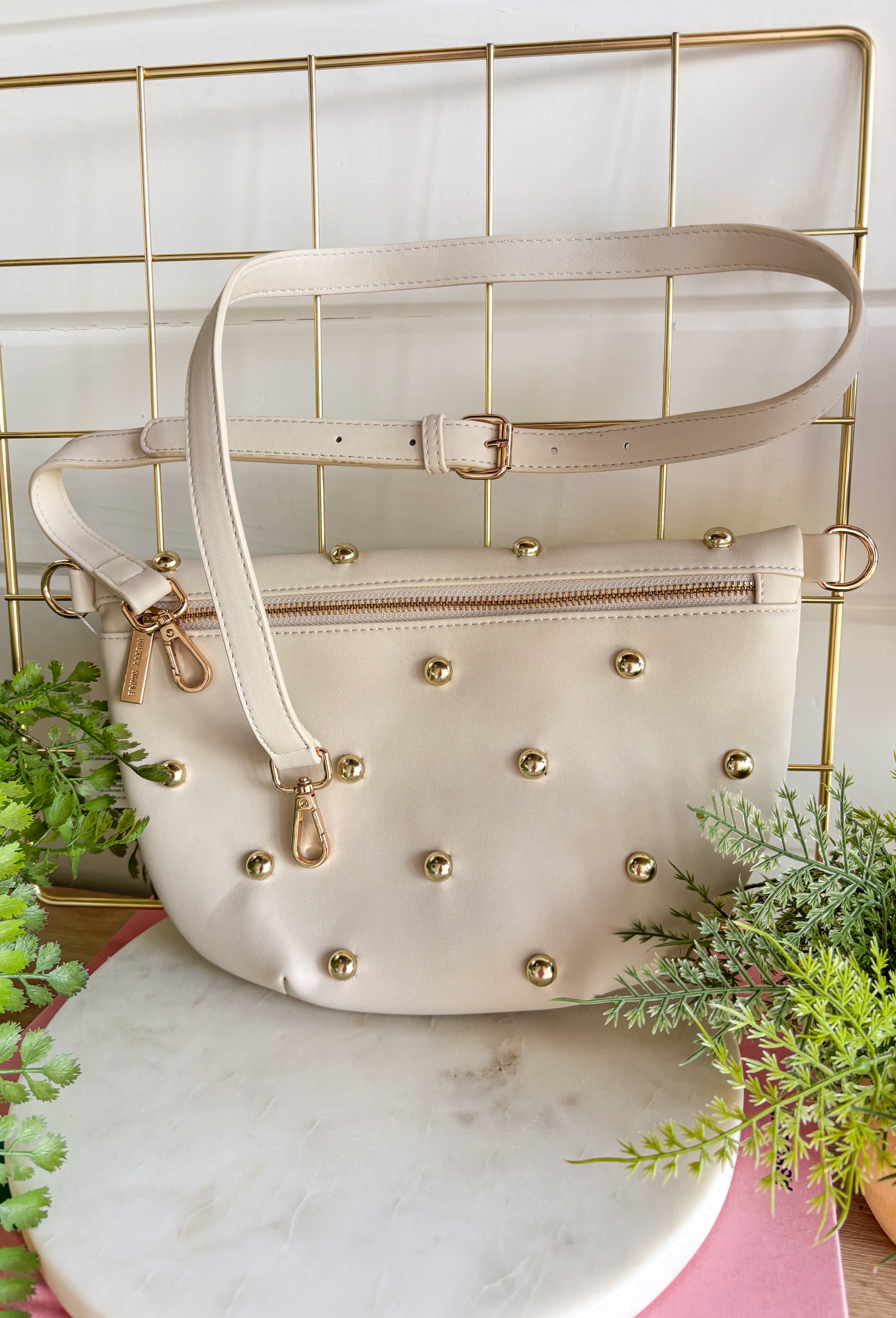 Everyone's favorite bag is back in a bold new design! The Studded Westlyn Bum Bag from Pretty Simple features the same hands-free style you love, now updated with eye-catching gold stud detailing for the perfect touch of edge. Crafted from soft vegan leather, this versatile bag can be worn as a belt bag or crossbody, making it the perfect companion for busy days, concerts, travel, shopping, and everyday adventures. Stylish, functional, and easy to wear, it's sure to become your new go-to accessory.
