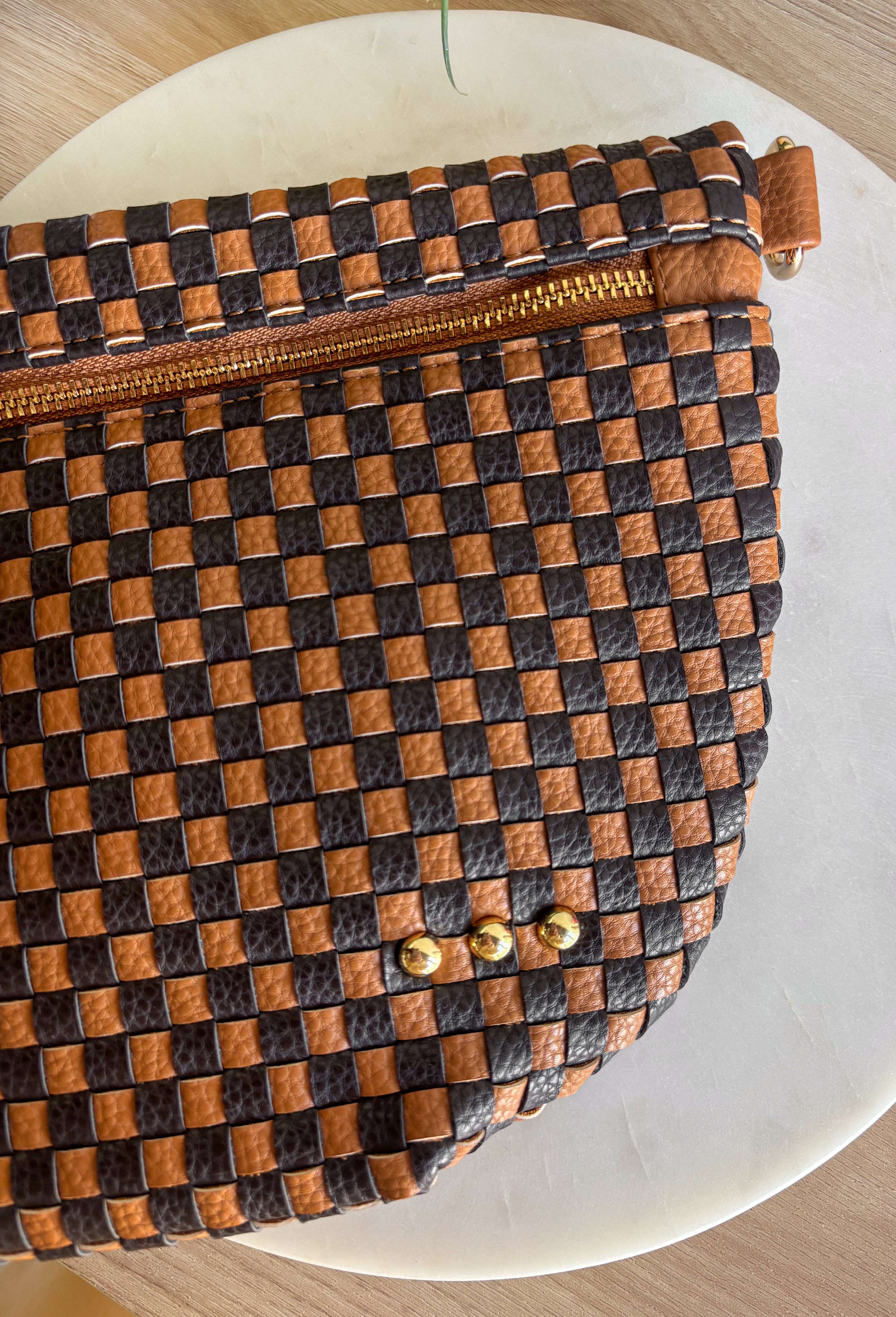 Meet the Westlyn&nbsp;Woven Bum Bag! Gorgeous woven vegan leather available in solid colors with a unique block design on the strap gives us edgy, rocker vibes. We also have it available in checkered prints, and metallic! Beautiful hardware with a zipper closure with beige and black chevron interior, and a zippered slash pocket on the inside. This crossbody bag is the perfect accessory to elevate any outfit!