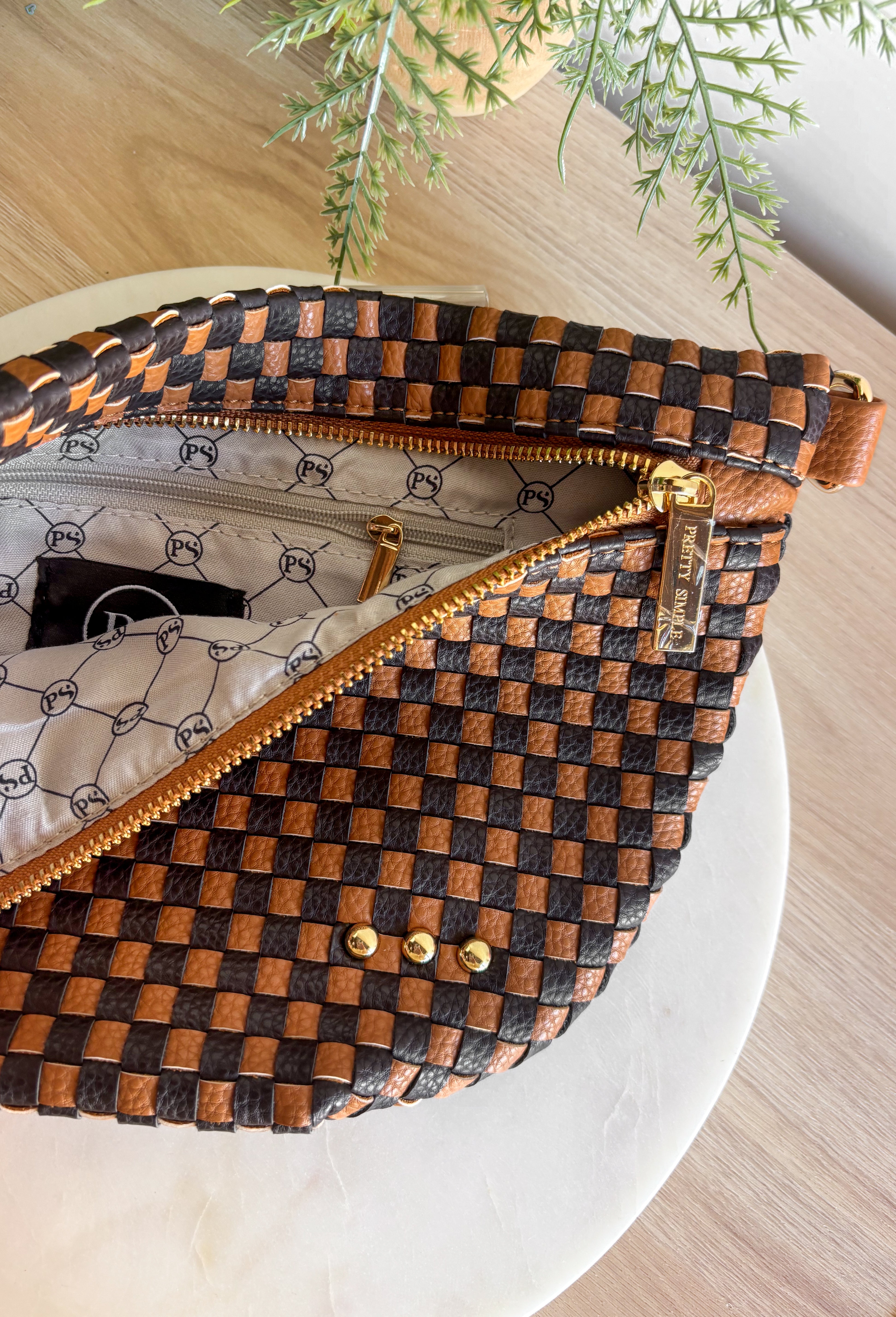 Meet the Westlyn&nbsp;Woven Bum Bag! Gorgeous woven vegan leather available in solid colors with a unique block design on the strap gives us edgy, rocker vibes. We also have it available in checkered prints, and metallic! Beautiful hardware with a zipper closure with beige and black chevron interior, and a zippered slash pocket on the inside. This crossbody bag is the perfect accessory to elevate any outfit!