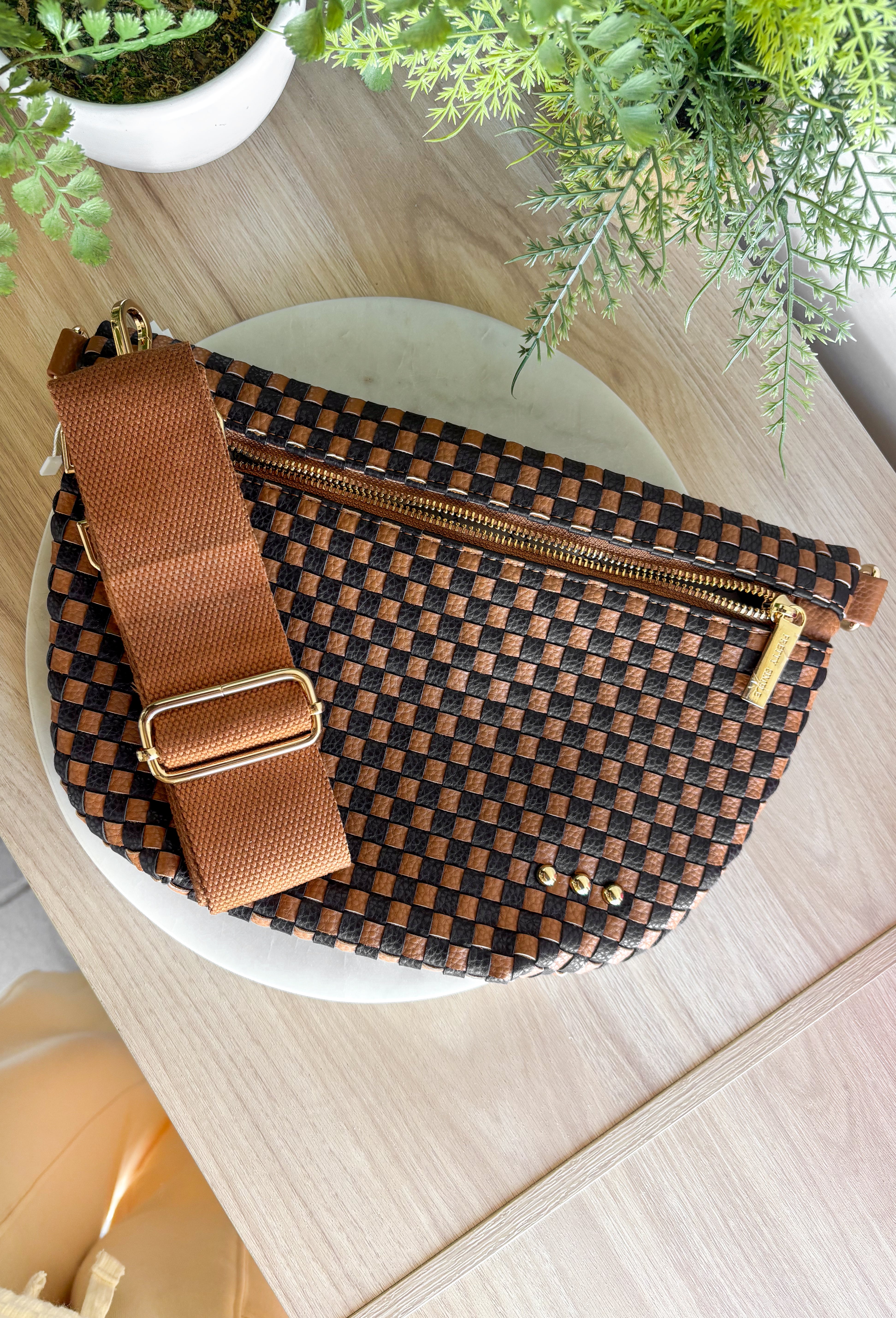 Meet the Westlyn&nbsp;Woven Bum Bag! Gorgeous woven vegan leather available in solid colors with a unique block design on the strap gives us edgy, rocker vibes. We also have it available in checkered prints, and metallic! Beautiful hardware with a zipper closure with beige and black chevron interior, and a zippered slash pocket on the inside. This crossbody bag is the perfect accessory to elevate any outfit!