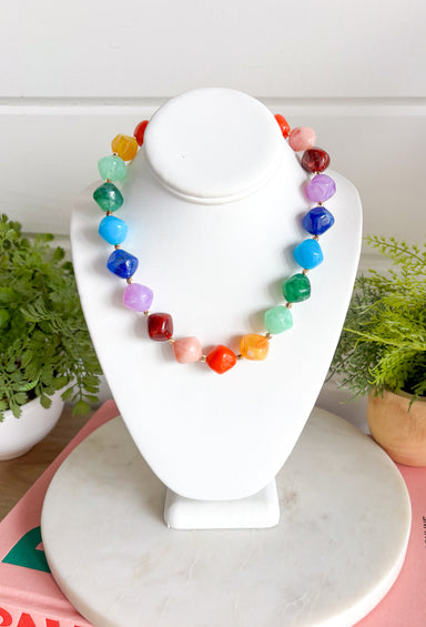 Brighten up any outfit with this colorful chunky beaded necklace that's full of personality and charm. Featuring vibrant beads in shades of navy, blue, green, purple, orange, yellow, and burgundy, this eye-catching accessory is accented with polished gold beads throughout for the perfect hint of shine. The versatile design makes it easy to wear with everything from casual sweaters to your favorite dresses, adding a fun pop of color wherever you go.