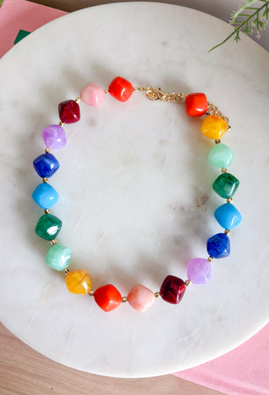 Brighten up any outfit with this colorful chunky beaded necklace that's full of personality and charm. Featuring vibrant beads in shades of navy, blue, green, purple, orange, yellow, and burgundy, this eye-catching accessory is accented with polished gold beads throughout for the perfect hint of shine. The versatile design makes it easy to wear with everything from casual sweaters to your favorite dresses, adding a fun pop of color wherever you go.