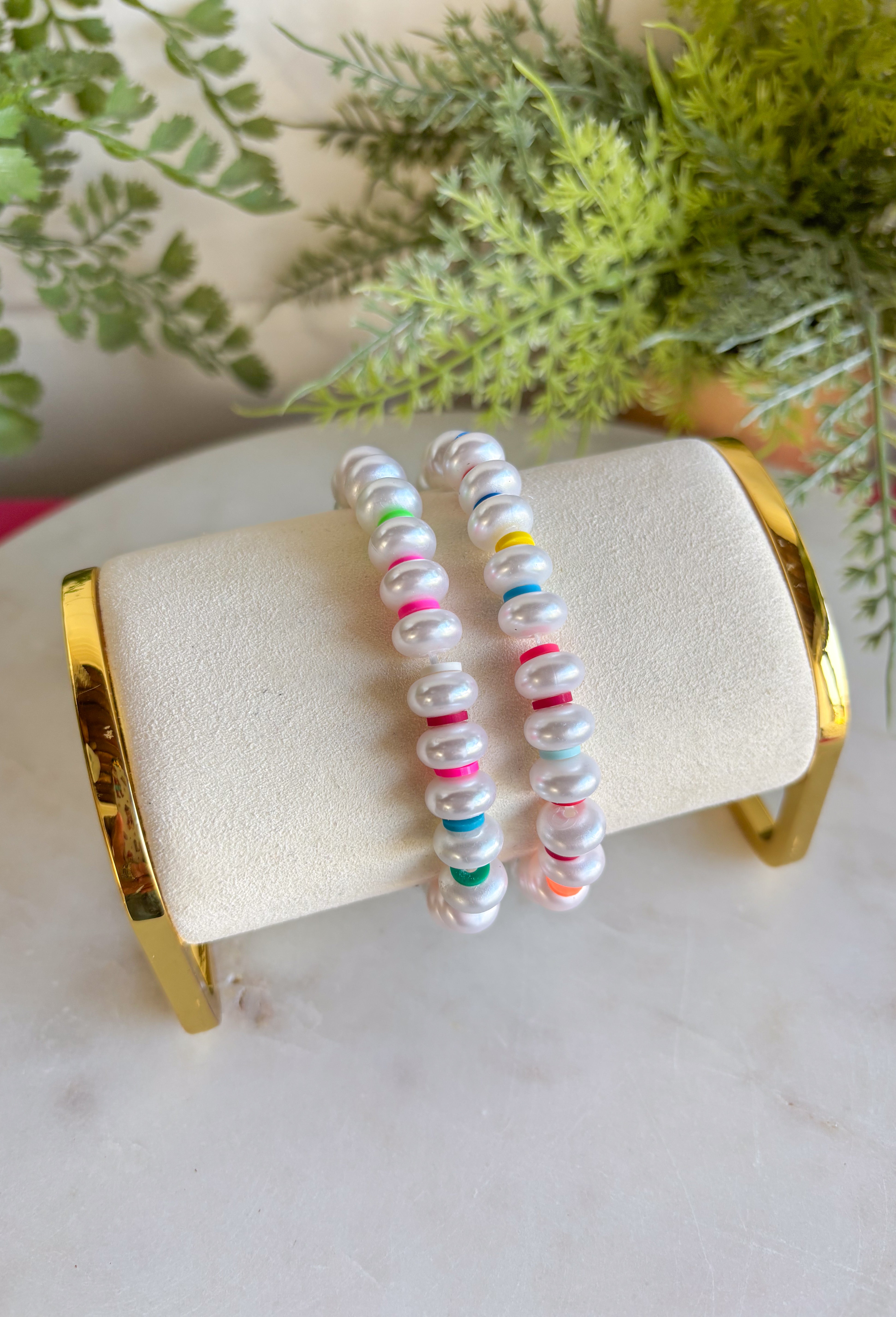 Bright, playful, and made for sunny days! This set of two pearl bracelets is the perfect pop of color for summer. Classic pearls are mixed with vibrant disc beads in pink, green, blue, orange, and red for a fun, feel-good stack that instantly livens up any outfit. Wear them together for a bold statement or mix and match with your favorite everyday bracelets for a layered look. Lightweight and easy to style, these are the kind of accessories you’ll reach for all season long.