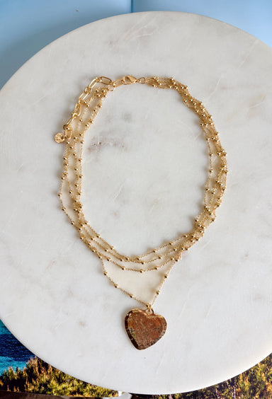 An effortless layered look with a sweet touch of shine! This gold layered necklace features delicate strands with small gold beads throughout, finished with a textured gold heart pendant that adds just the right amount of charm. The layered design makes styling easy—giving you that perfectly stacked look in one simple piece. Whether worn with a casual outfit or dressed up for a special moment, this necklace adds a soft, feminine glow to any look.