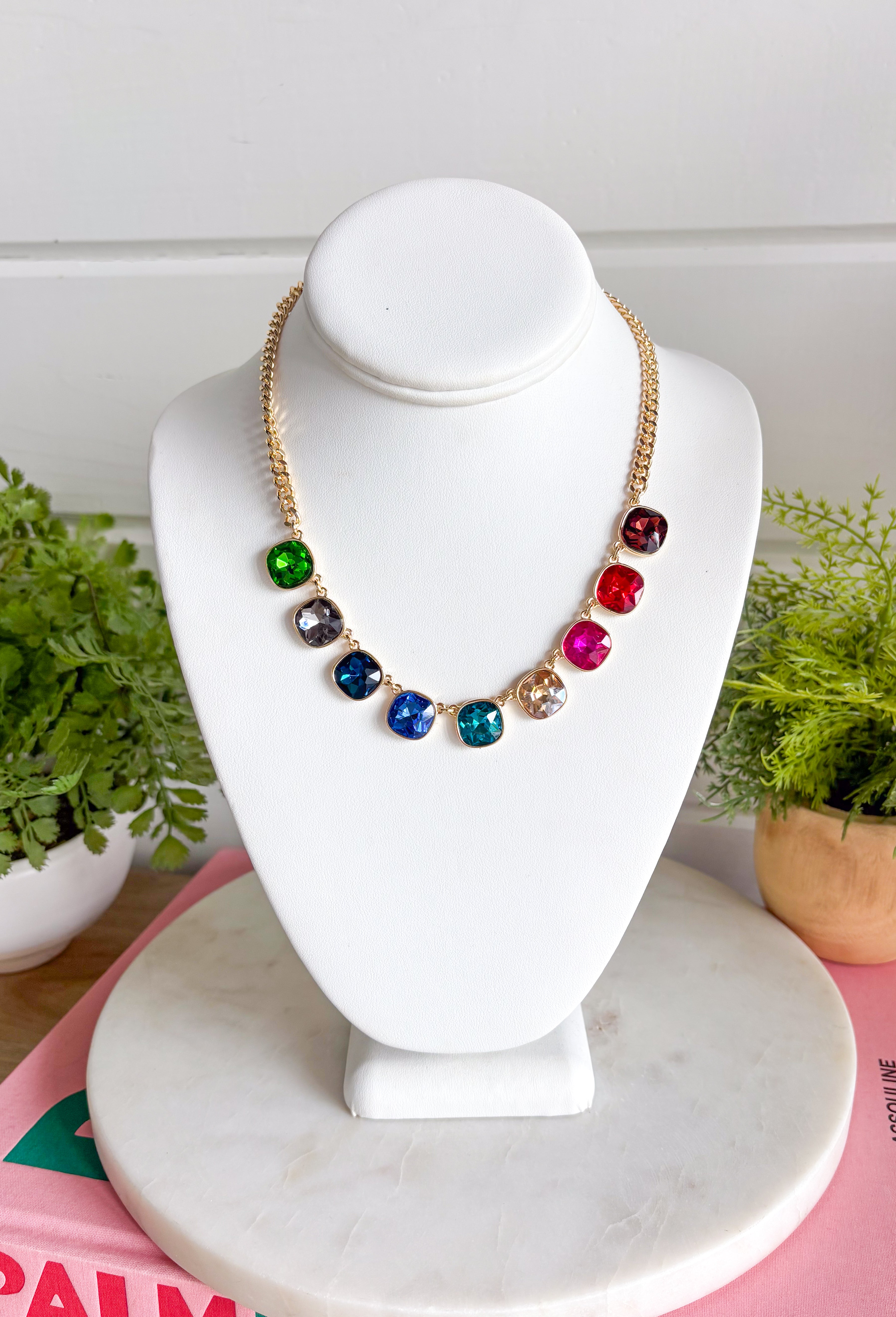Add a vibrant finishing touch to your jewelry collection with this stunning gold chain necklace. Featuring colorful gemstones in shades of green, blue, gold, pink, red, and burgundy, this chic piece brings the perfect balance of timeless style and playful color. The delicate gold chain makes it easy to wear on its own or layered with your favorite necklaces, creating an effortlessly polished look for any occasion.