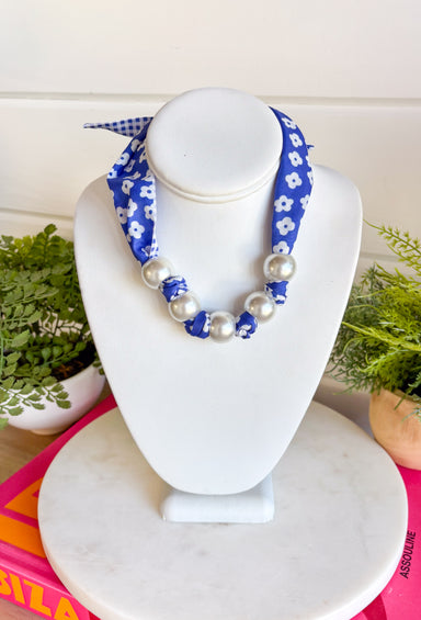 Add a fresh twist to your accessory collection with this versatile scarf necklace that's full of timeless charm. Featuring a beautiful blue and white floral print on one side and a classic blue and white gingham print on the reverse, this unique piece lets you switch up your look with ease. Chunky pearl detailing adds a chic touch, while the scarf tie design allows you to adjust the fit exactly how you like it. 