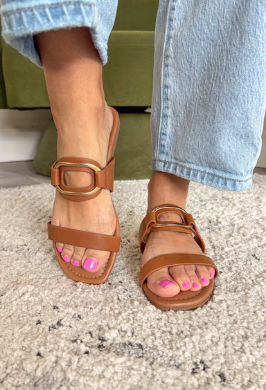 These cognac brown slide sandals are the effortless finishing touch every summer outfit needs! Designed with a sleek silhouette and gold oval buckle detail, they bring just the right amount of polish while still keeping things easy and wearable. The neutral tone makes them incredibly versatile—perfect for pairing with everything from dresses to denim. Whether you're heading to brunch, running errands, or packing for vacation, these slides are a go-to for any occasion. 